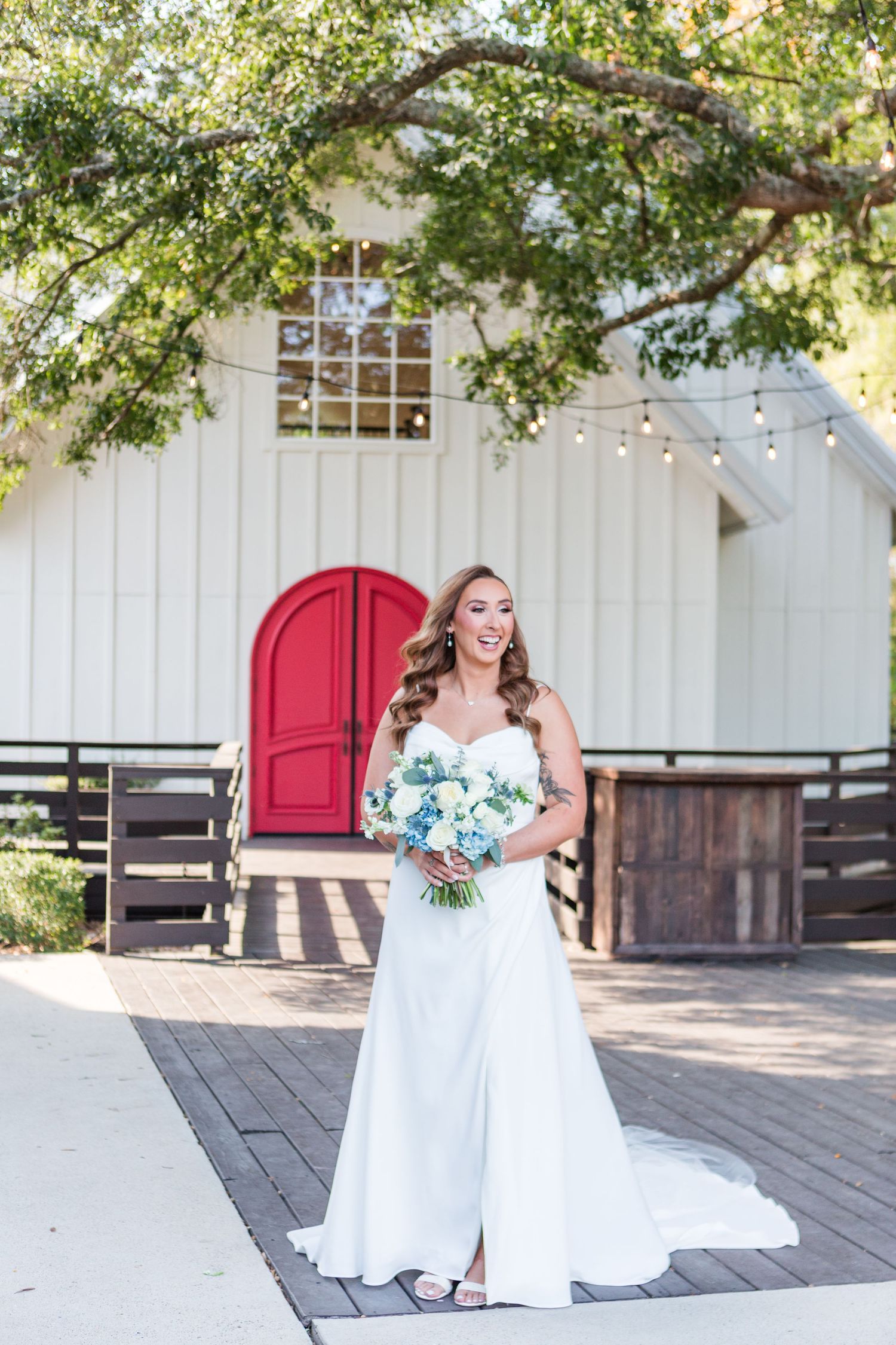 Wedding scene in front of white building with red door and string lights.