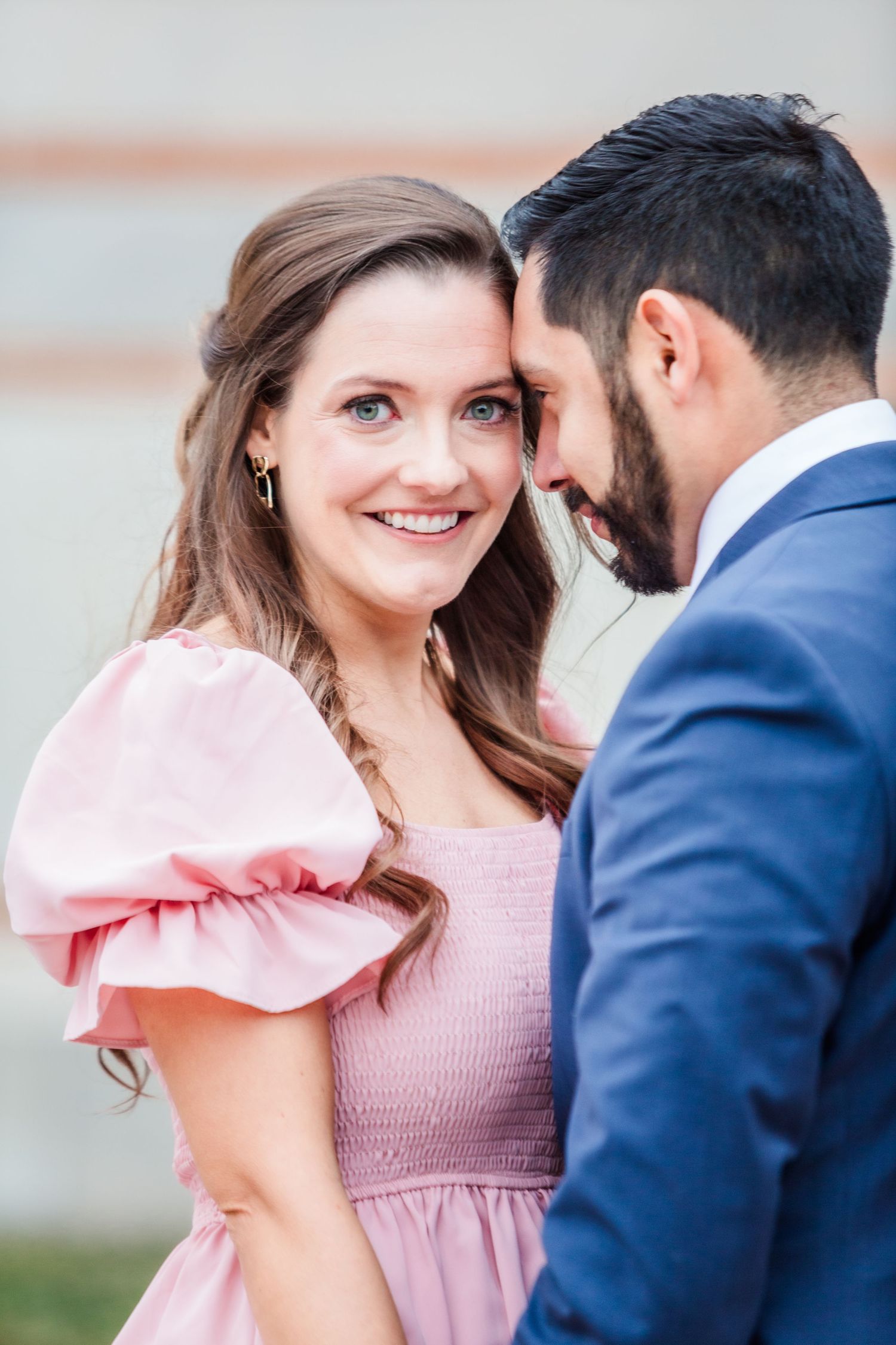 A tender moment shared between a couple wearing pink dress and navy suit.