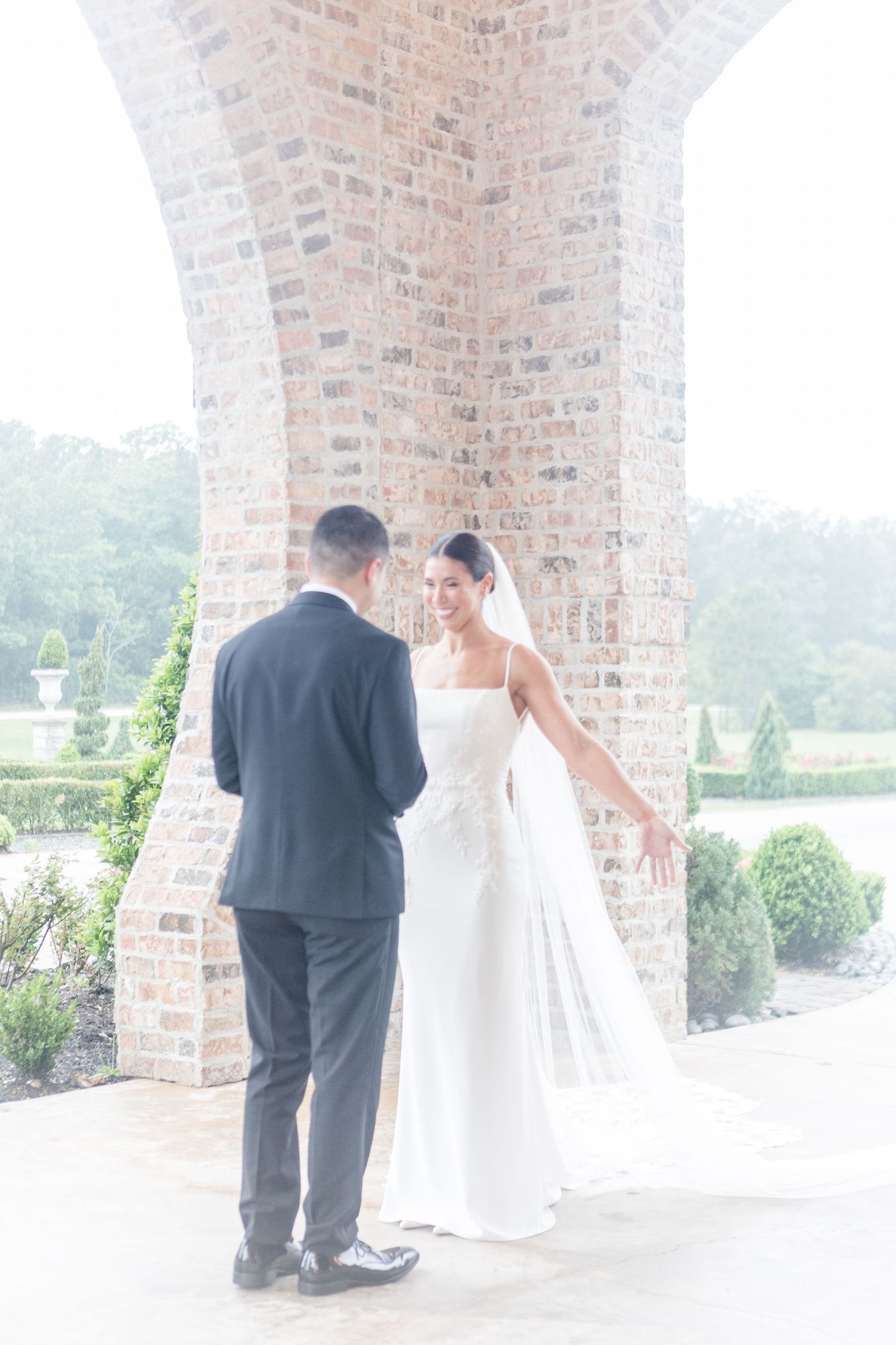 Emotional first look scene between newlyweds on a brick-lined balcony.