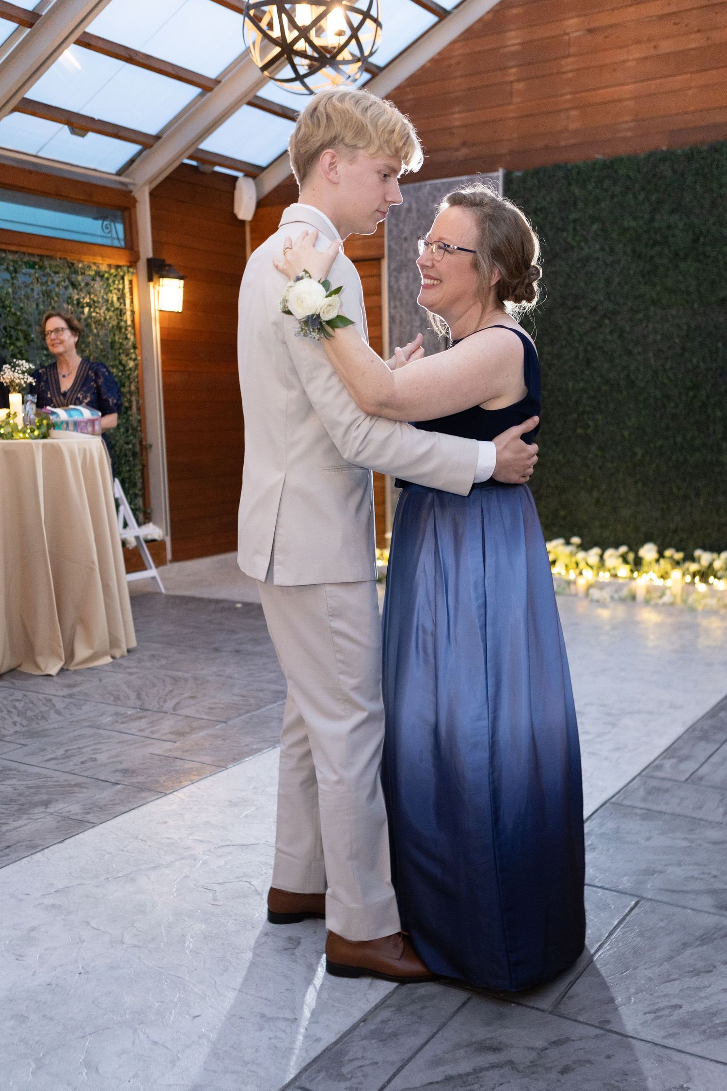 Wedding reception dance featuring guests in formal attire under wooden beams and skylights.