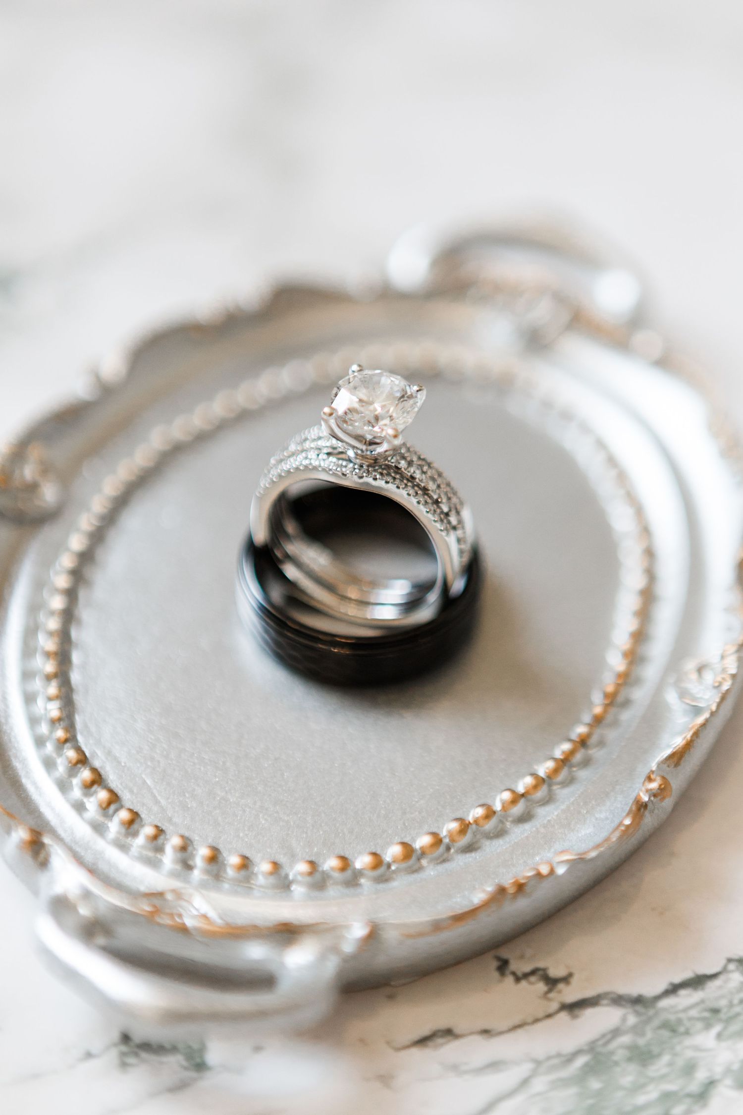 Close-up sequence of wedding rings with decorative borders on white textured surfaces.