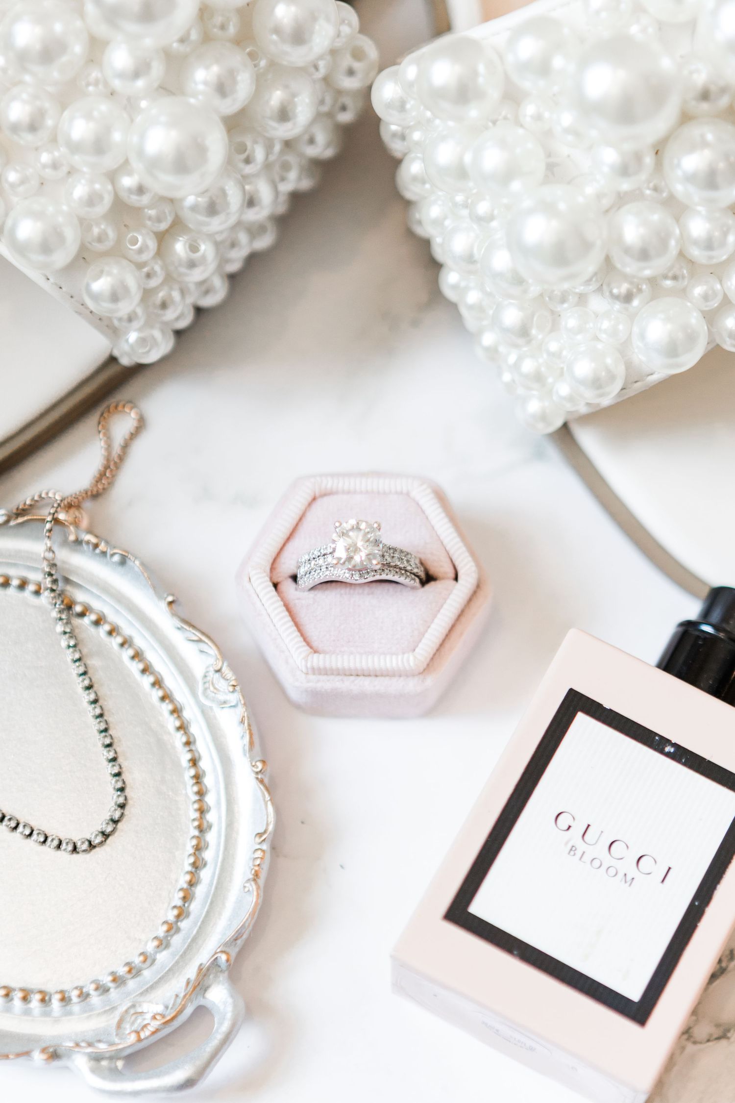 Wedding accessories including pearl decorations, rings, and Gucci branding on white background.