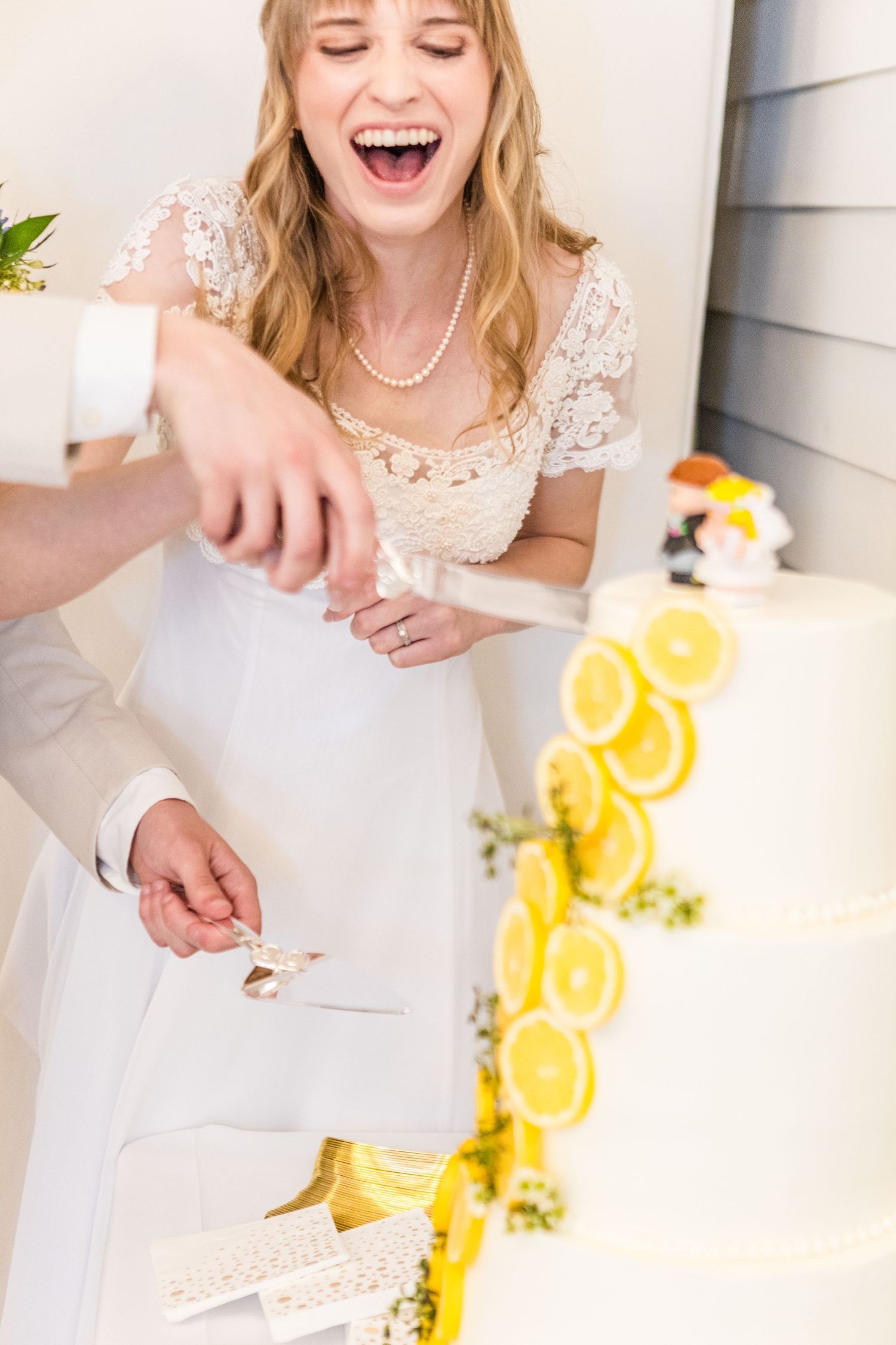 Cake cutting celebration at wedding with lemon-decorated tiered cake.