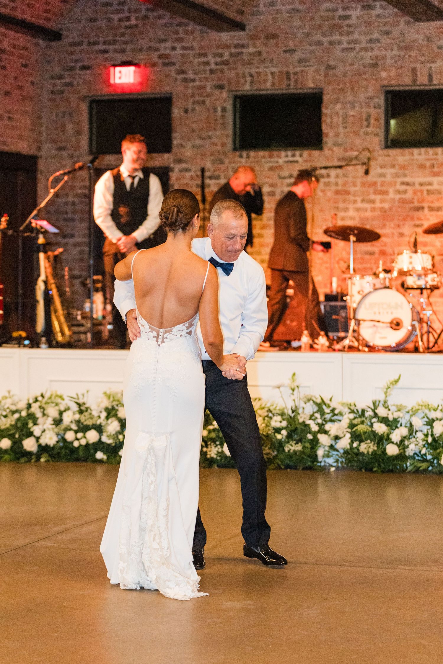 Dancing celebration on a wooden floor with exposed brick walls and stage lighting.