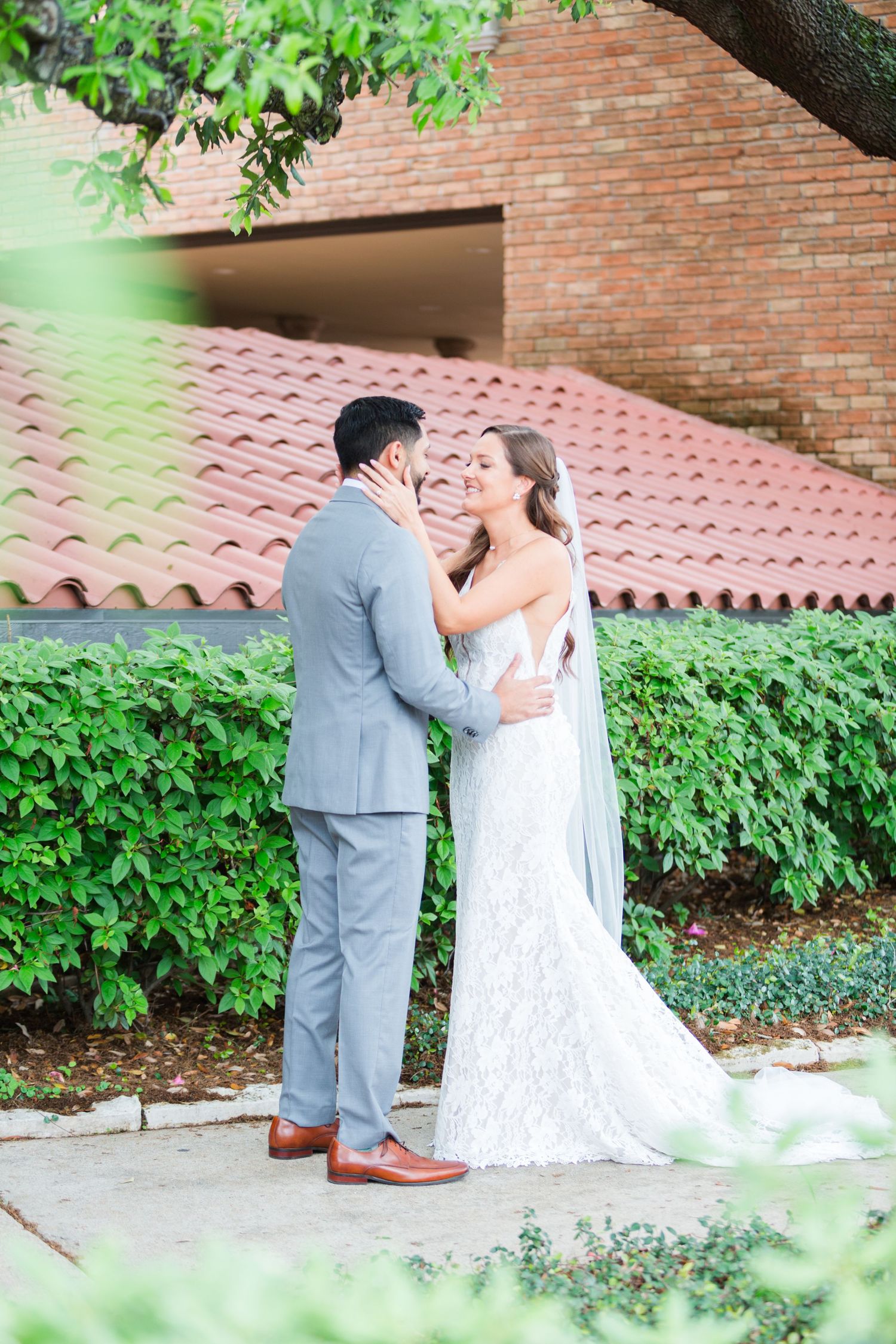Romantic scene against brick wall backdrop with terra cotta roof tiles and green foliage.
