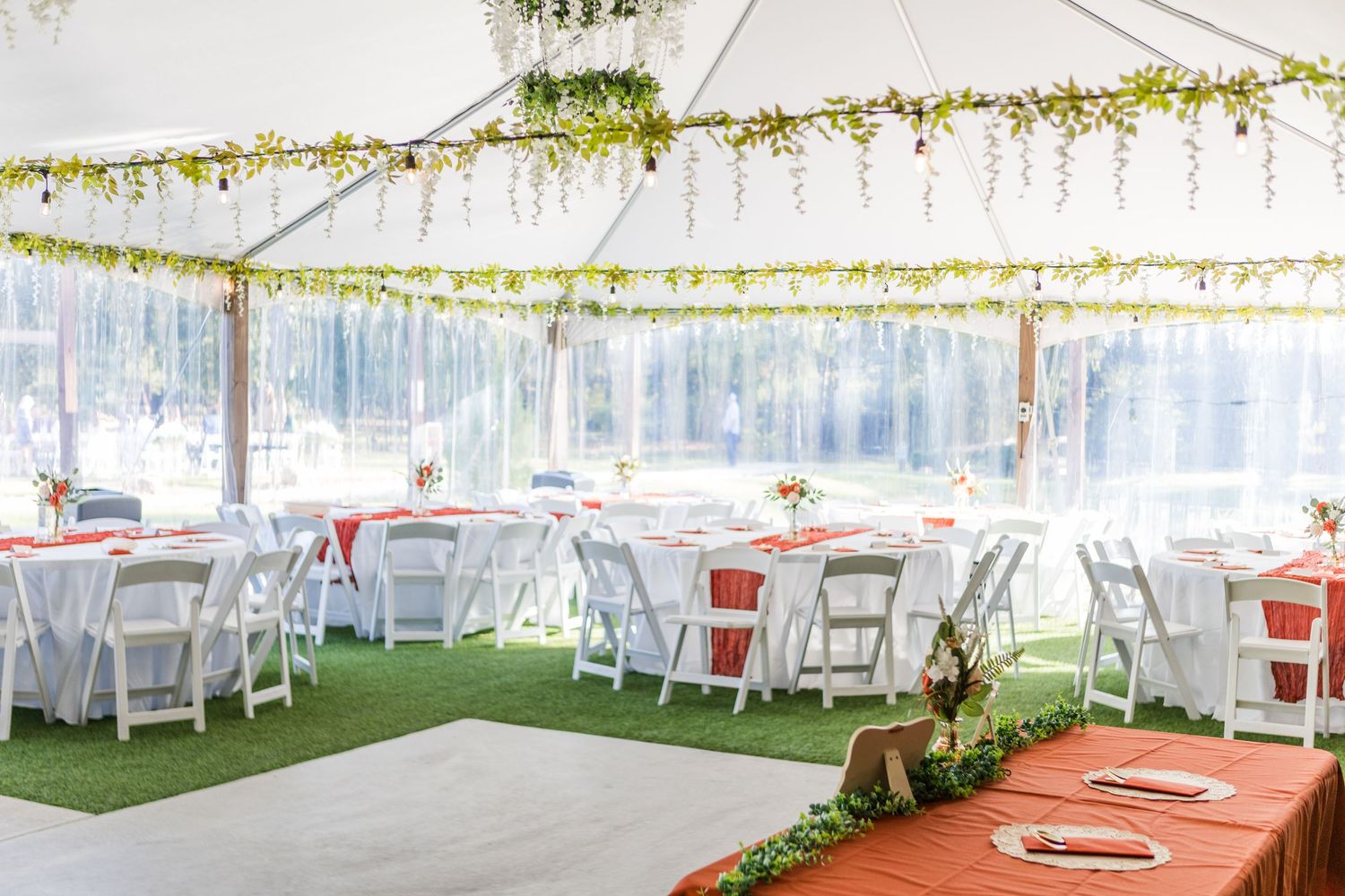White wedding tent decorated with elegant draping and coral table linens for an outdoor reception setup.