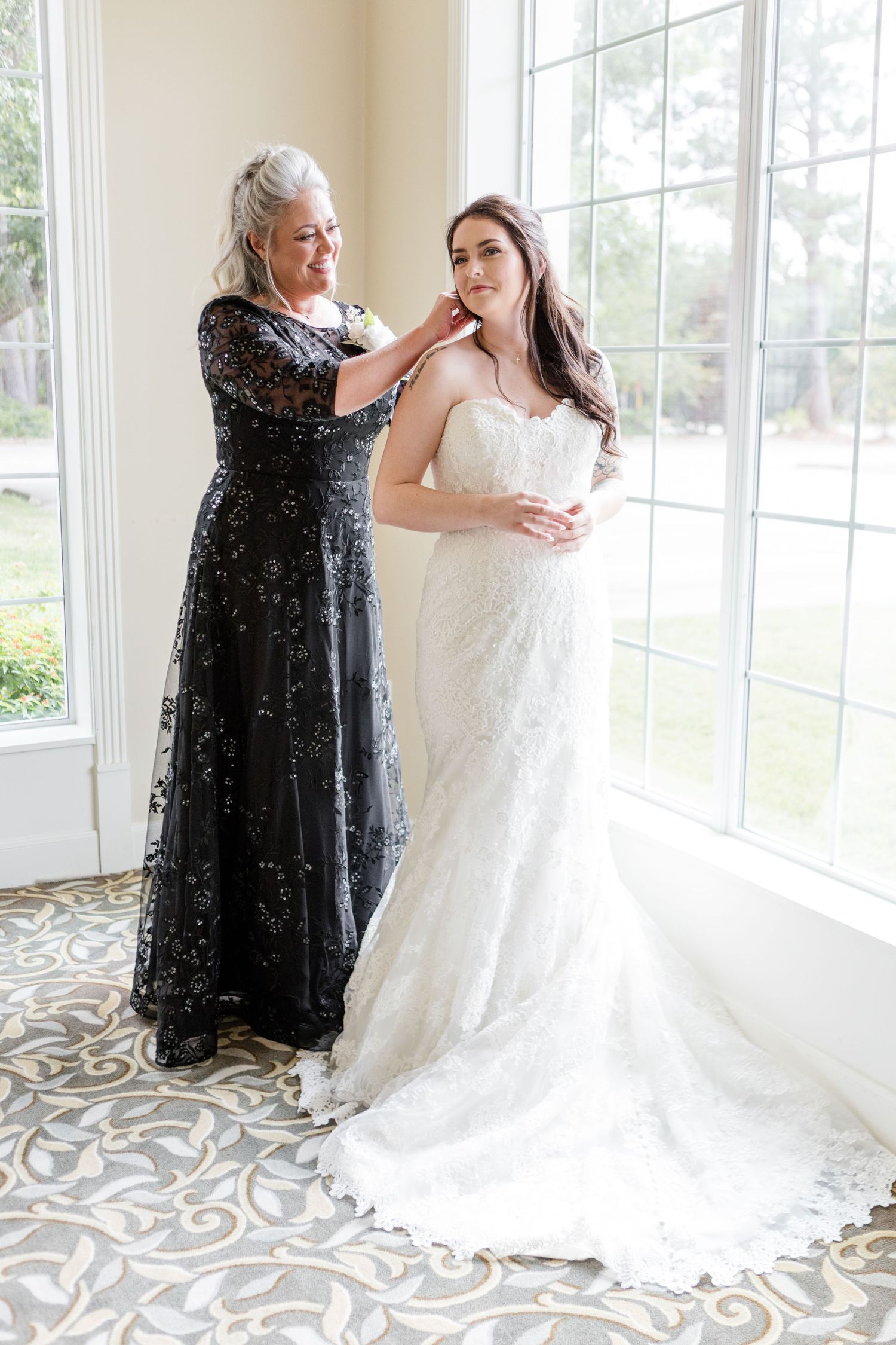 Wedding dress fitting scene with sparkly black dress in background by sunny windows.