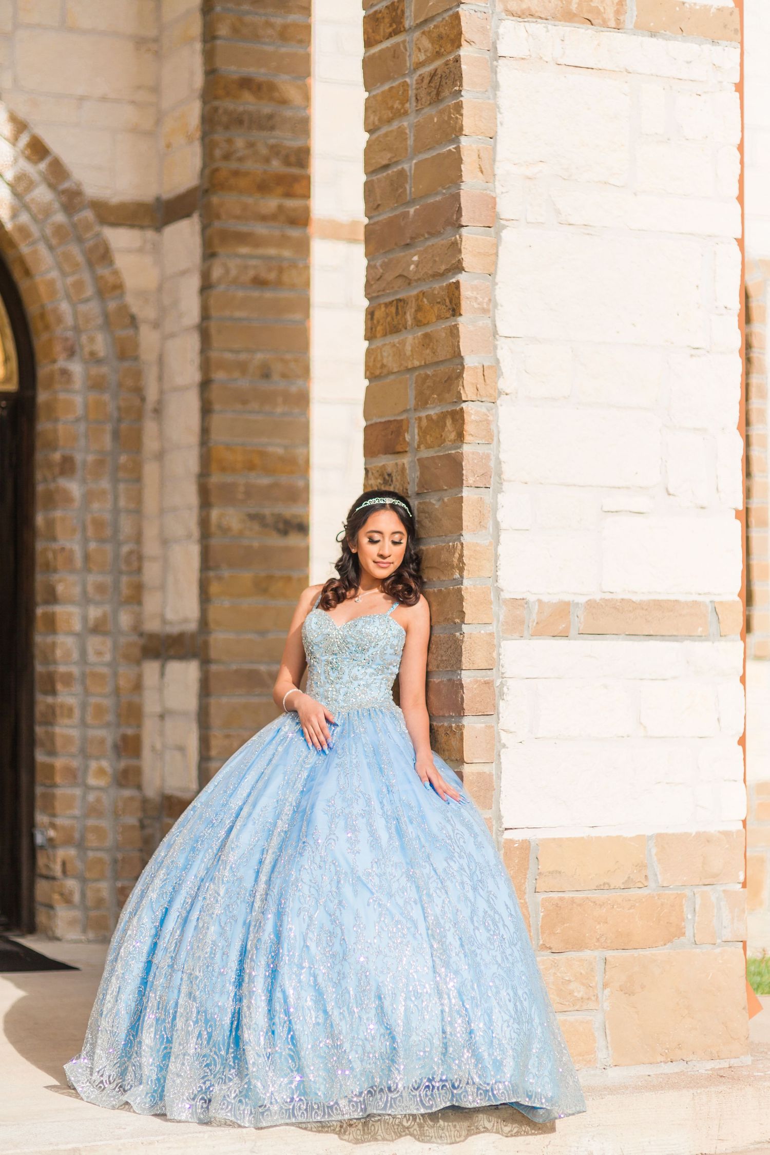 Light blue ball gown photographed against historic stone archways and brick columns.