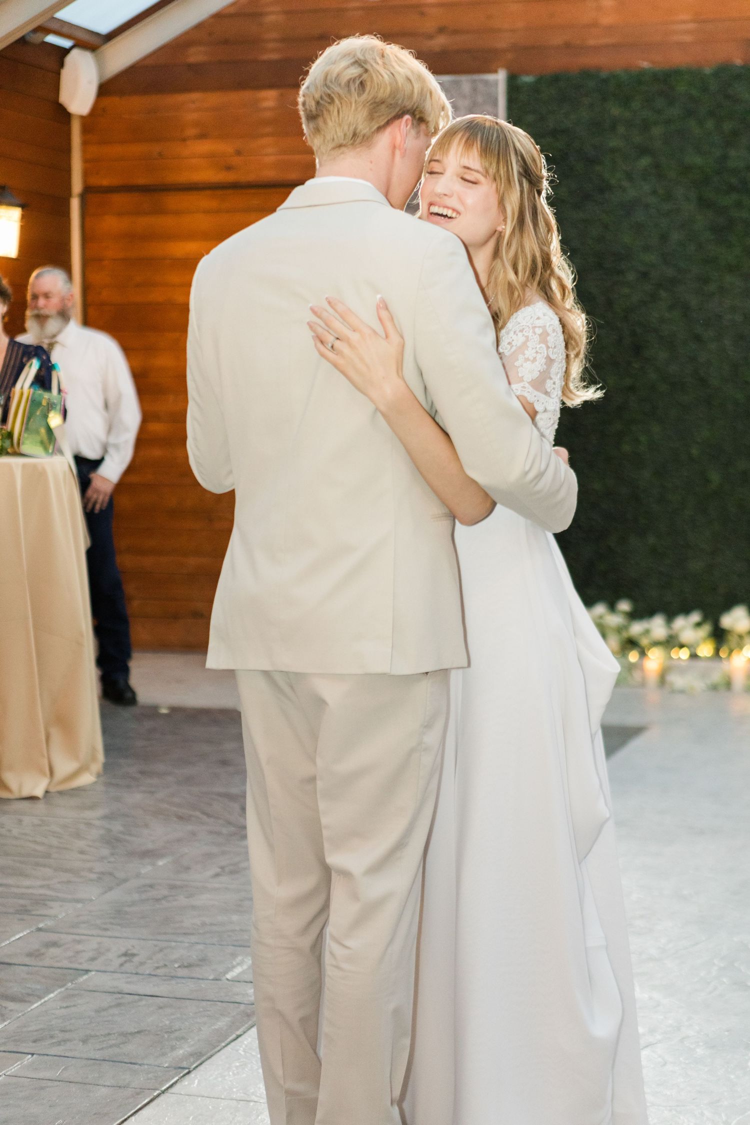 Wedding couple sharing an intimate dance moment beneath warm lighting in a rustic venue.