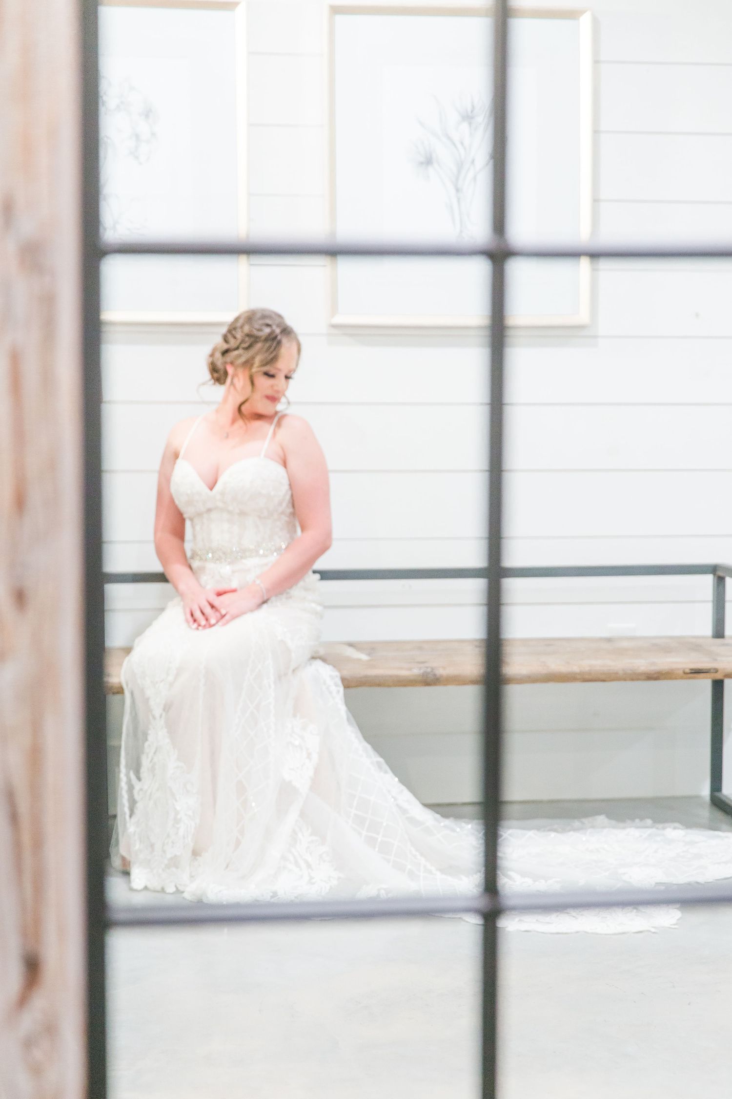 Beautiful white bridal gown details shown through window reflections in an elegant indoor space.