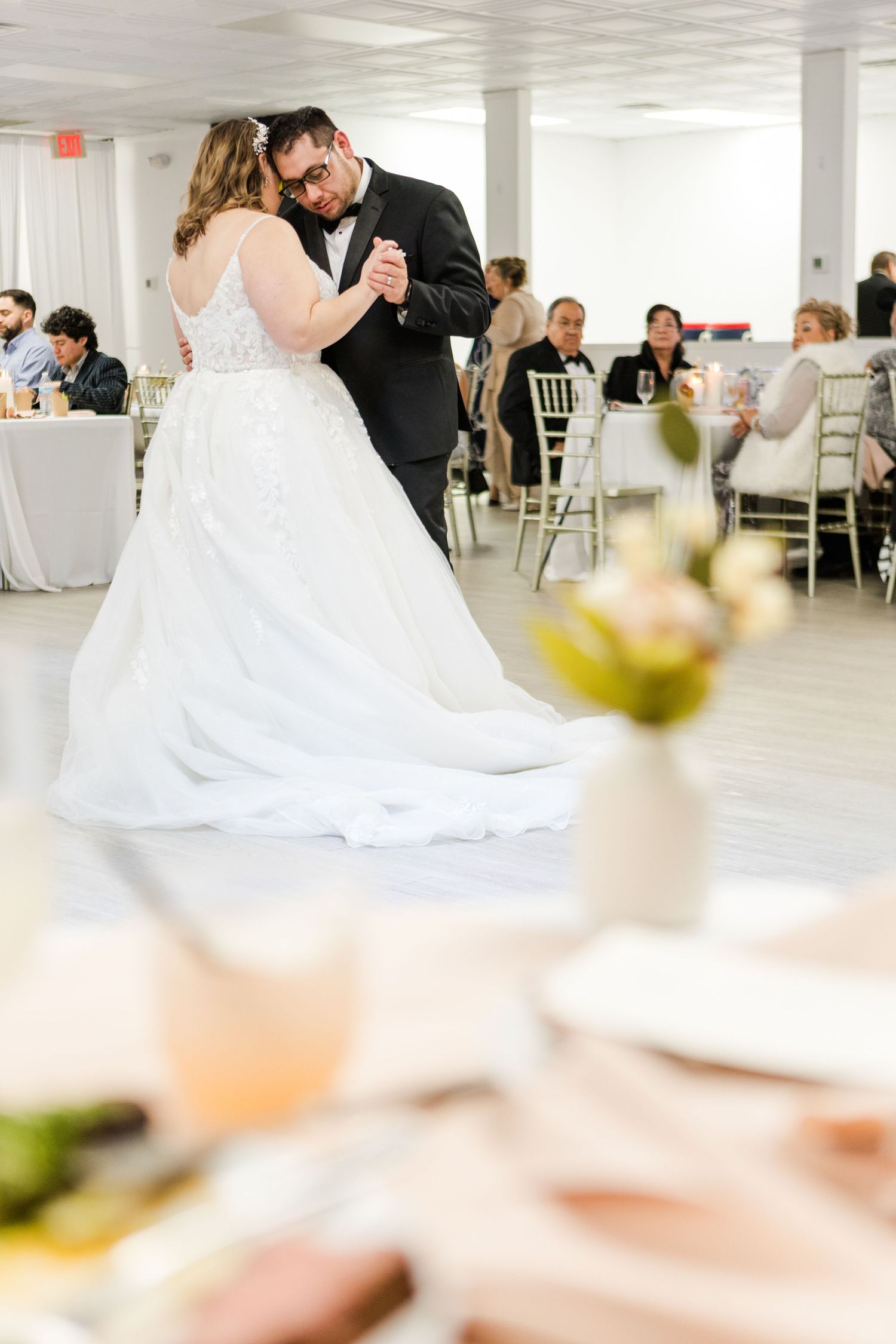 Wedding guests watch as dancers twirl across a white reception hall.