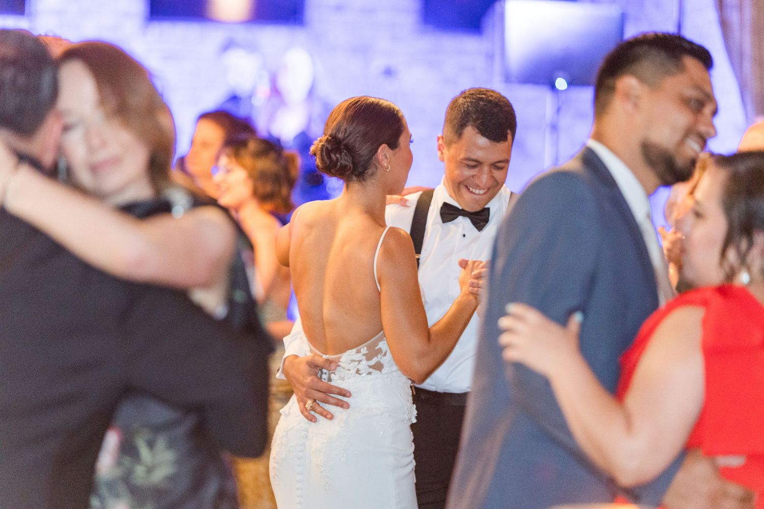 Couples dancing together at an elegantly lit wedding reception.