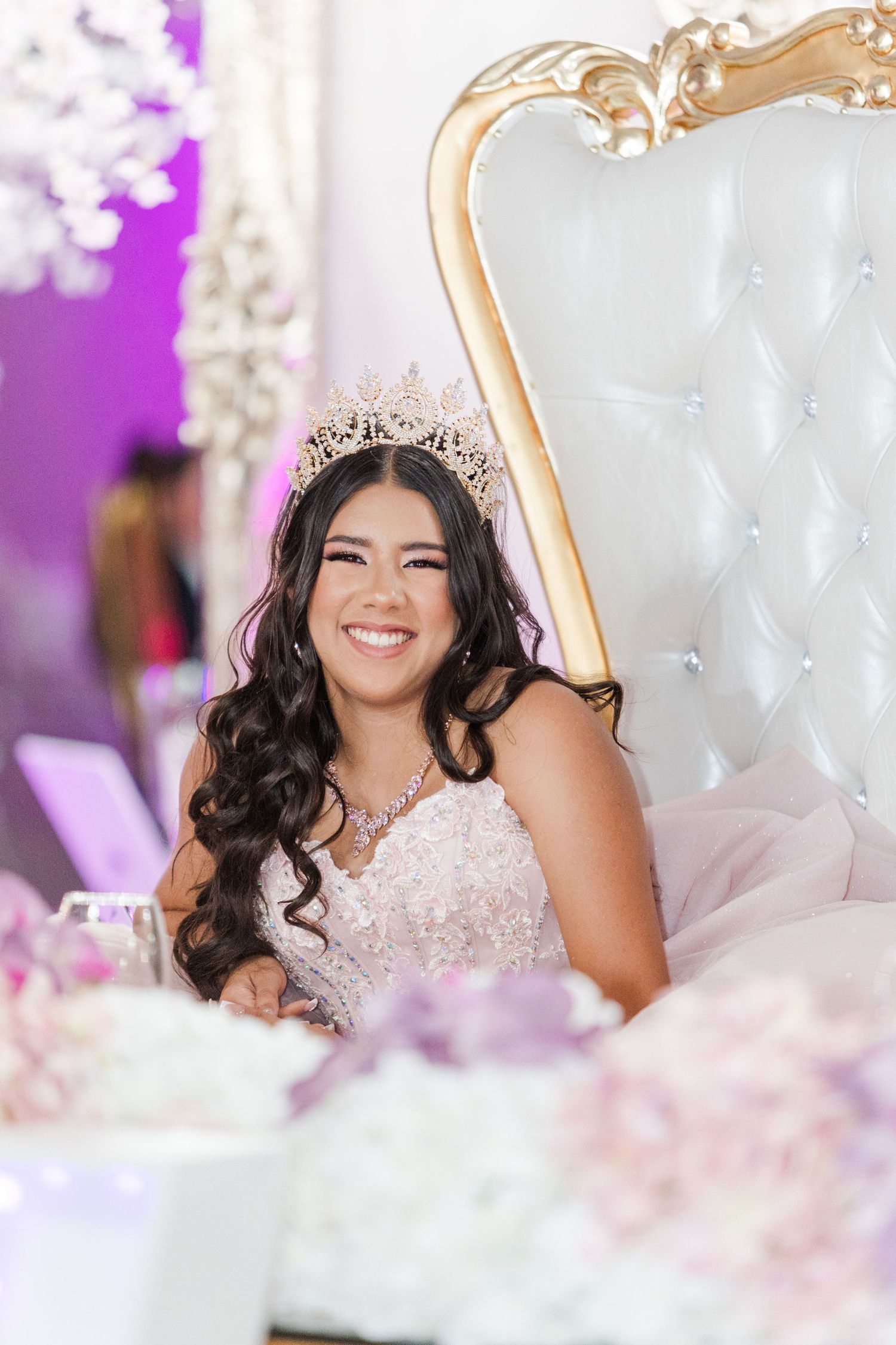 Elegant celebration setup with white tufted throne chair and purple lighting accents.