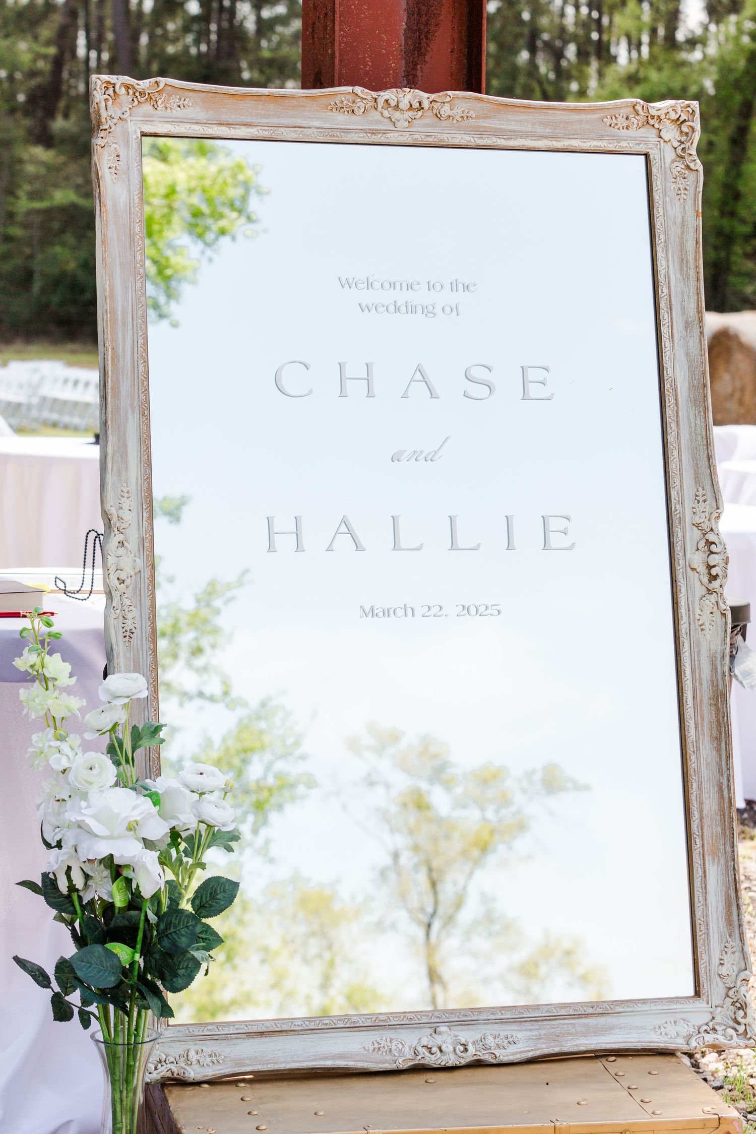 Elegant wedding signage in vintage frames displayed outdoors with floral decorations.
