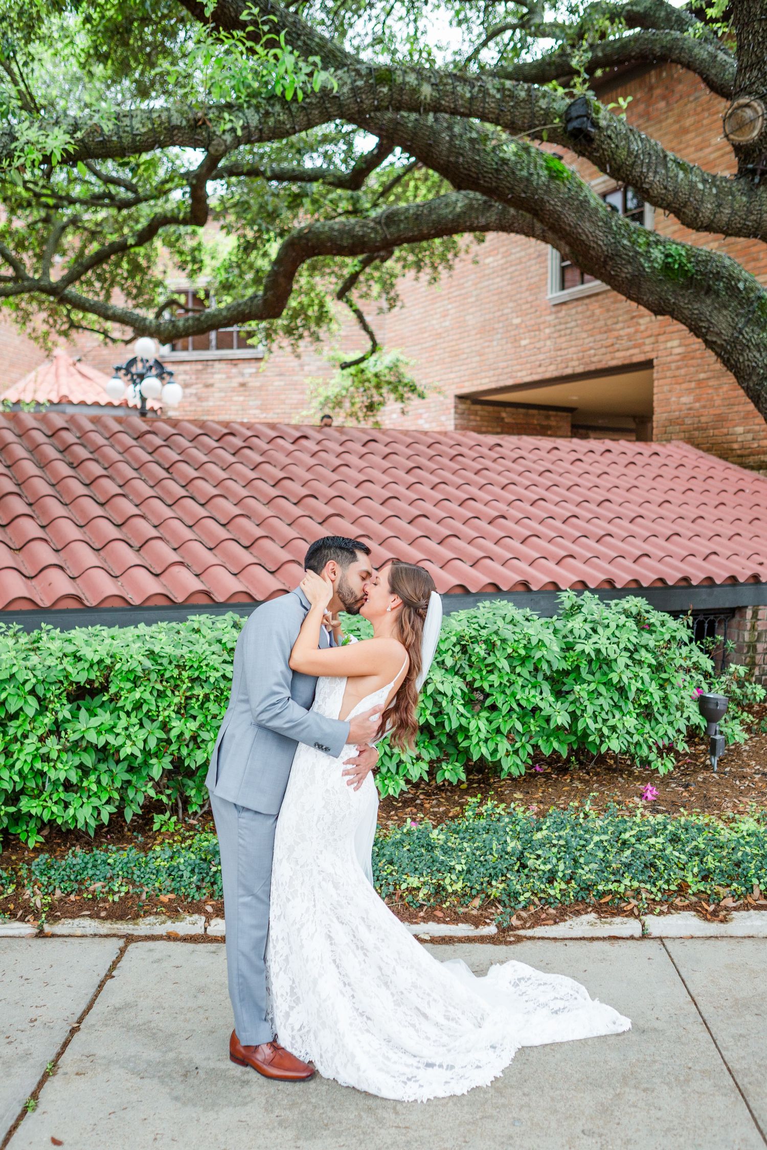 Romantic wedding photos taken beside brick wall with climbing ivy and terra cotta roof.