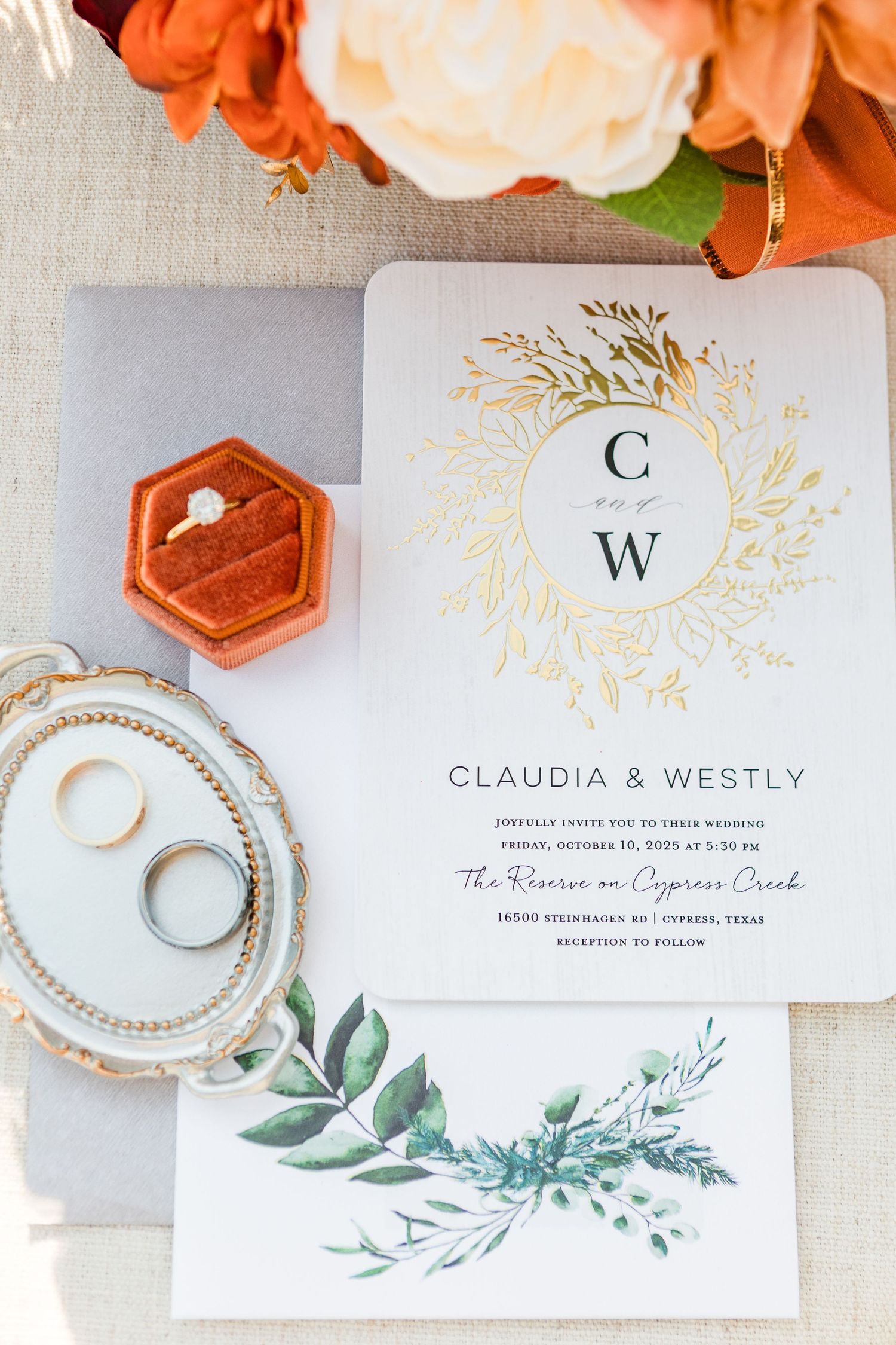Elegant white and gold wedding invitation suite with delicate watercolor greenery and orange floral accents.