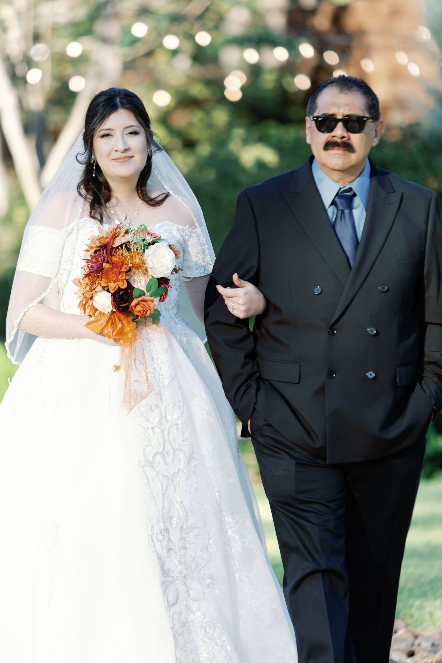 A wedding scene outdoors with autumn-colored bouquet details and formal attire.