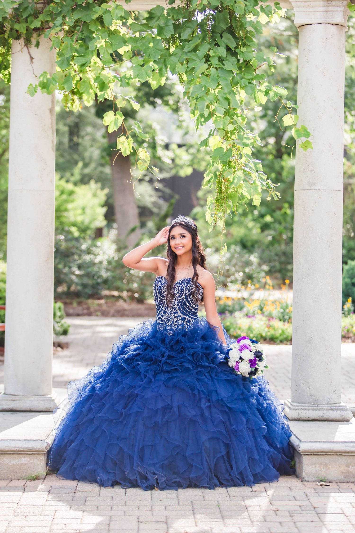 Stunning sapphire blue ballgown dress photographed in an elegant outdoor colonnade setting.