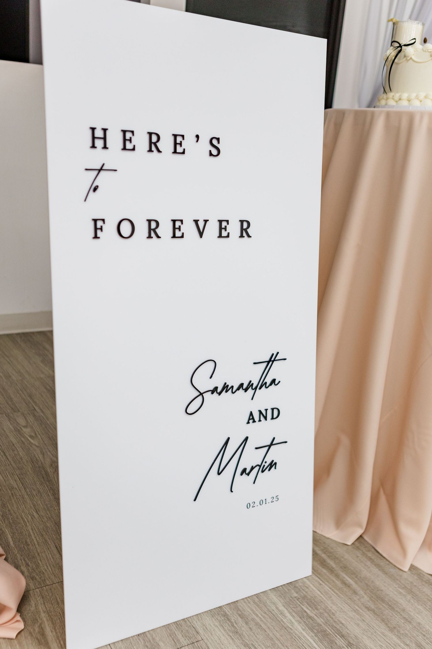 Minimalist white wedding sign with elegant black typography displaying couple's names.