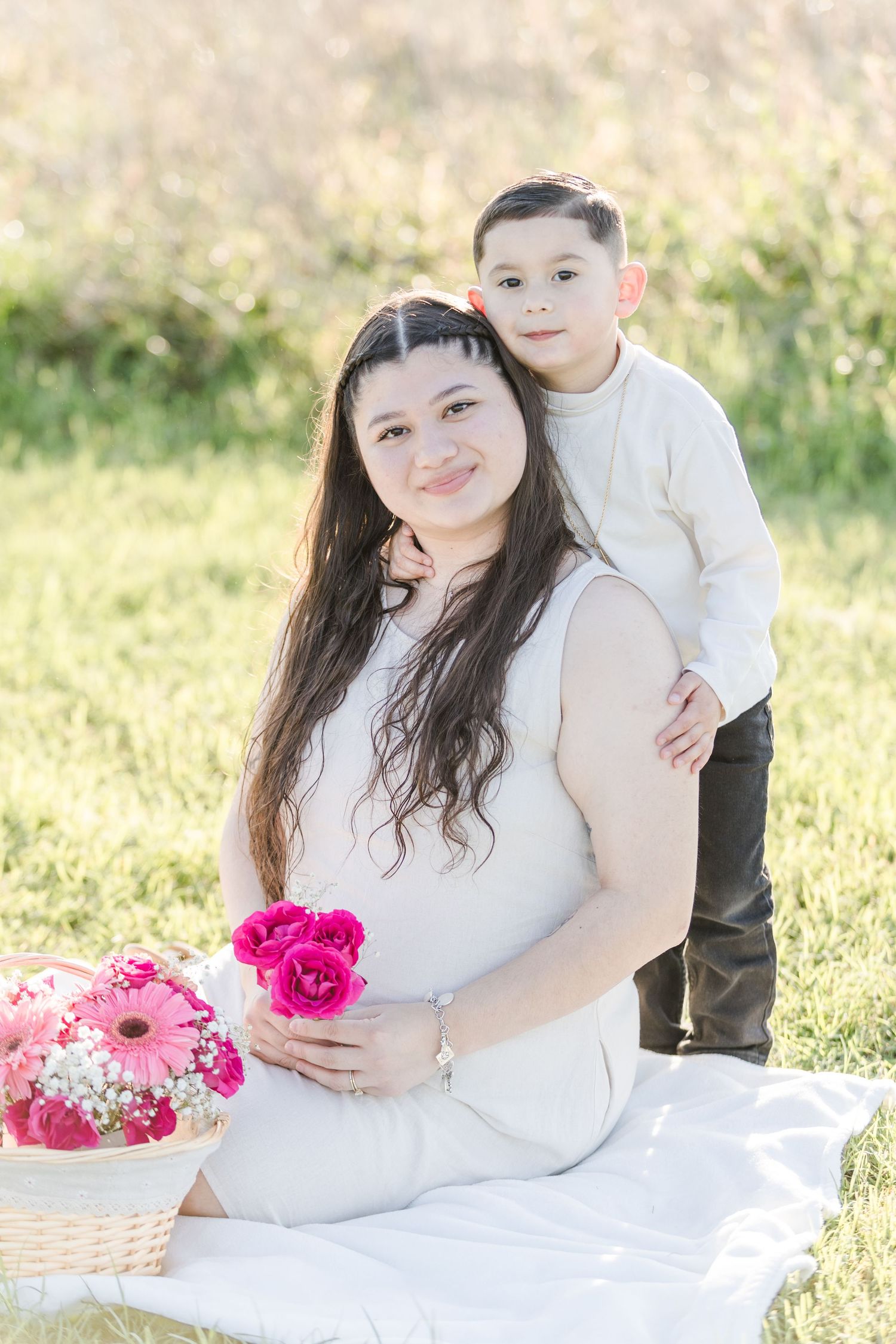 Family photo session on white blanket with pink floral arrangements.