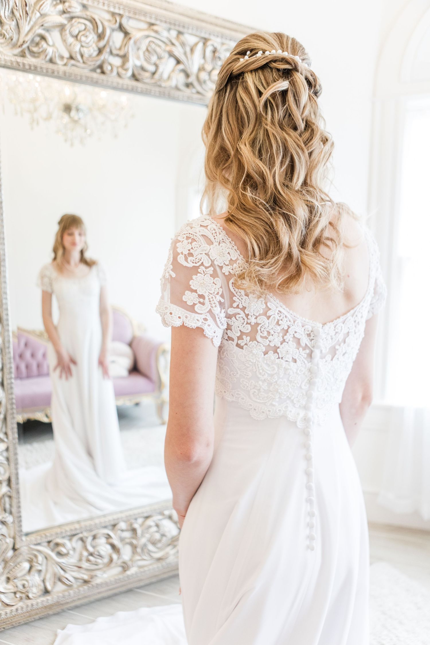 Ornate mirror reflections capture the detailed lace back of a wedding gown.