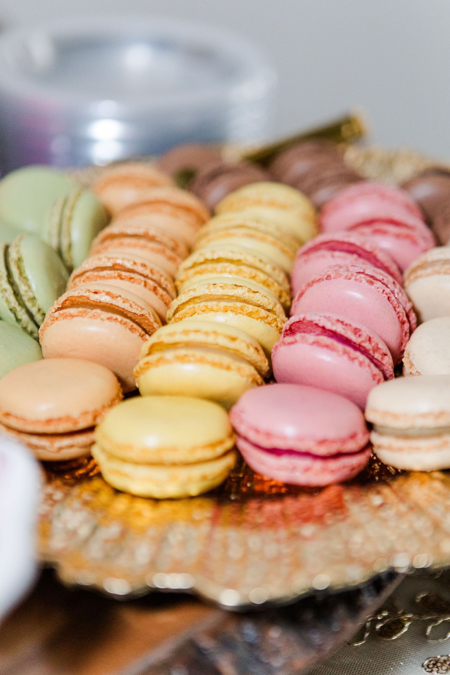 Pastel colored French macarons lined up showing peach, yellow, pink and white varieties.