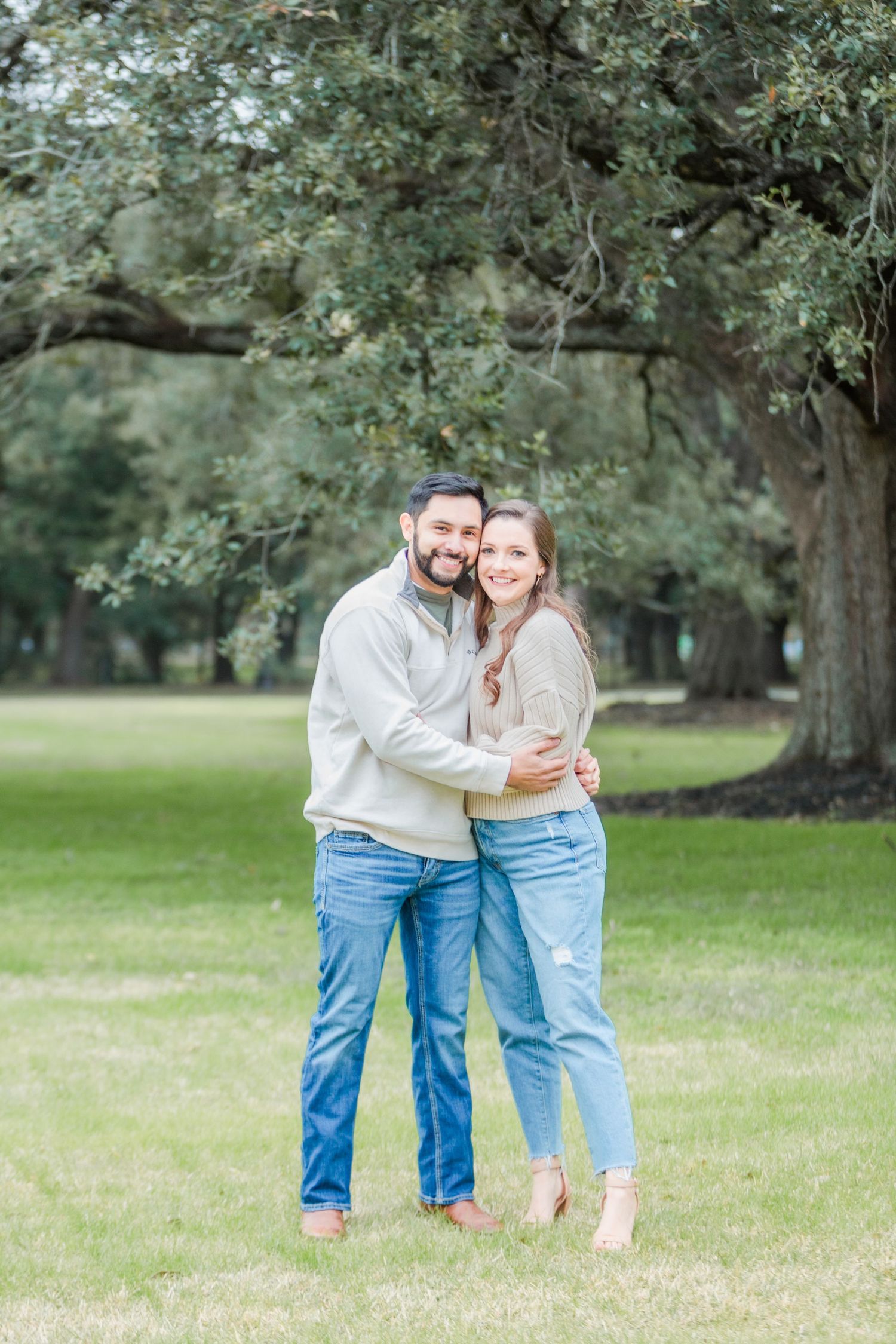 Couple in matching casual outfits embracing in green park setting.
