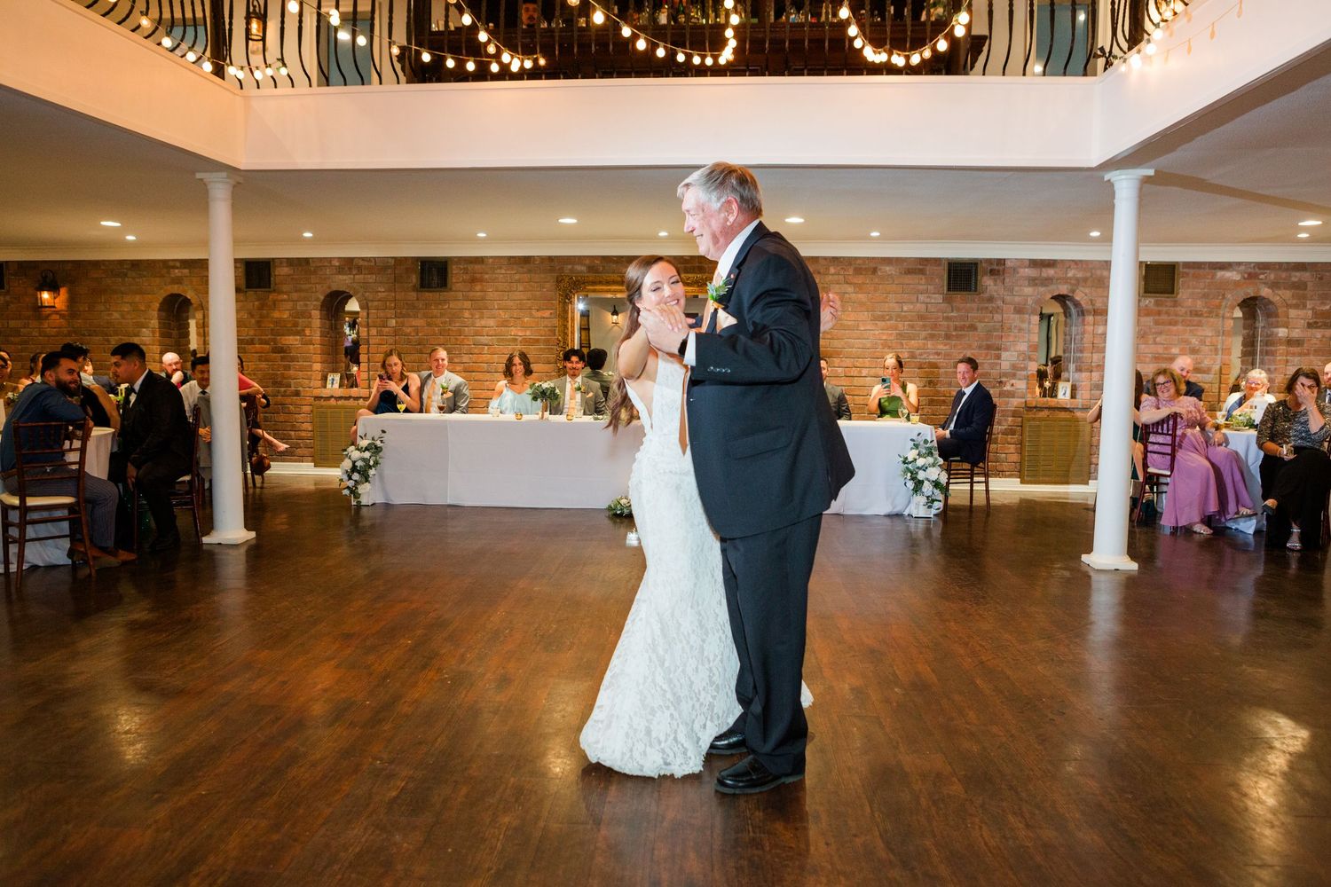Wedding reception panorama with twinkle lights and hardwood dance floor.