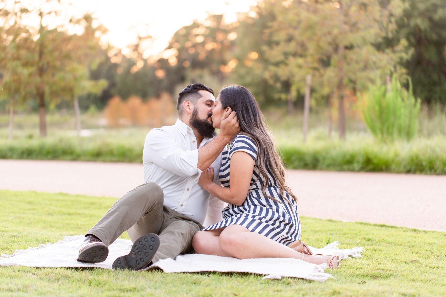 Romantic couple lying on grass in golden autumn sunlight during outdoor photo session.
