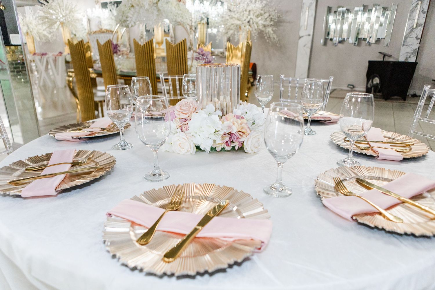 Elegant white and gold dining table setup with crystal chandeliers and floral centerpieces.