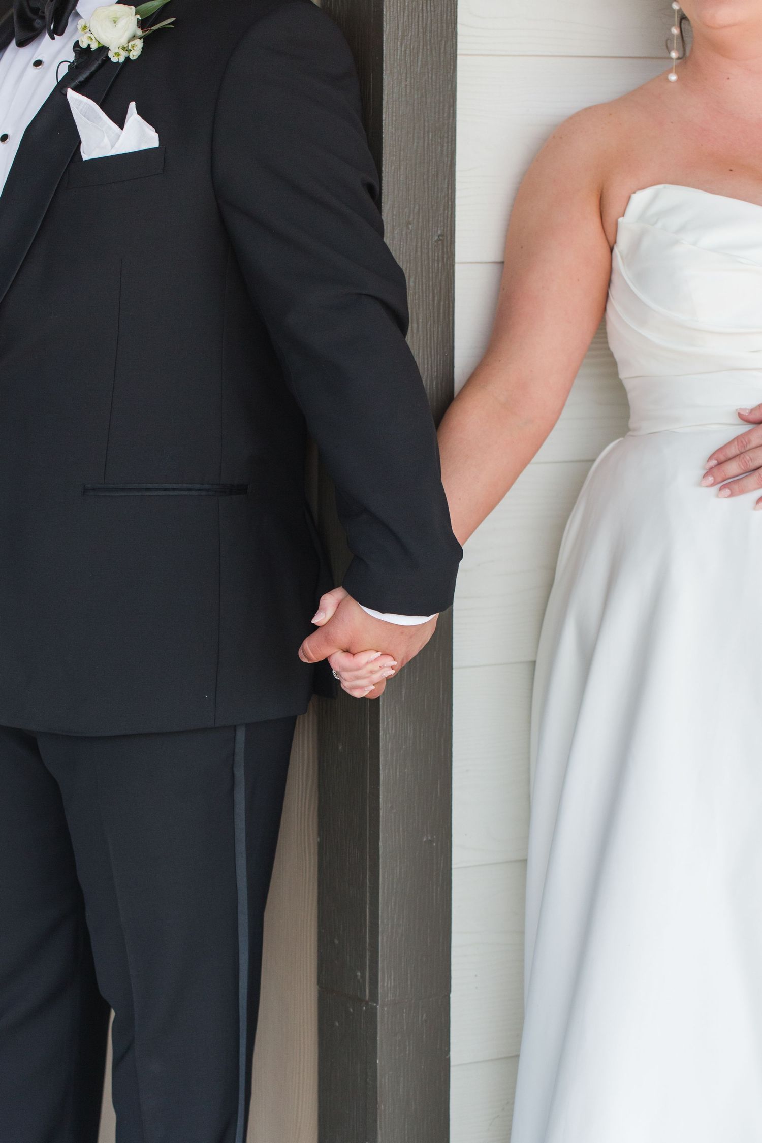 Wedding couple holds hands while standing on opposite sides of a column.
