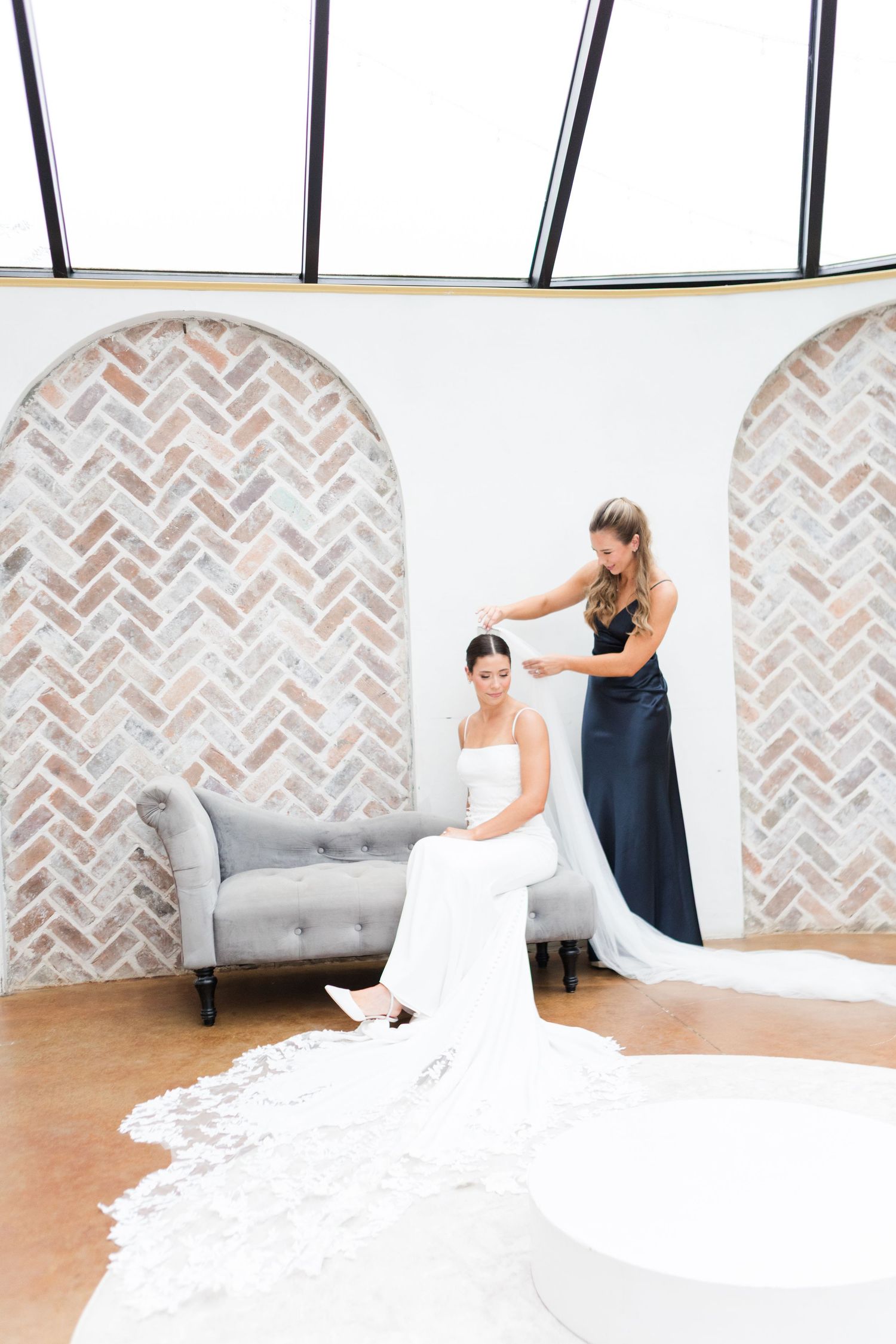 White wedding dress flowing across wooden floor in bright sunlit room.