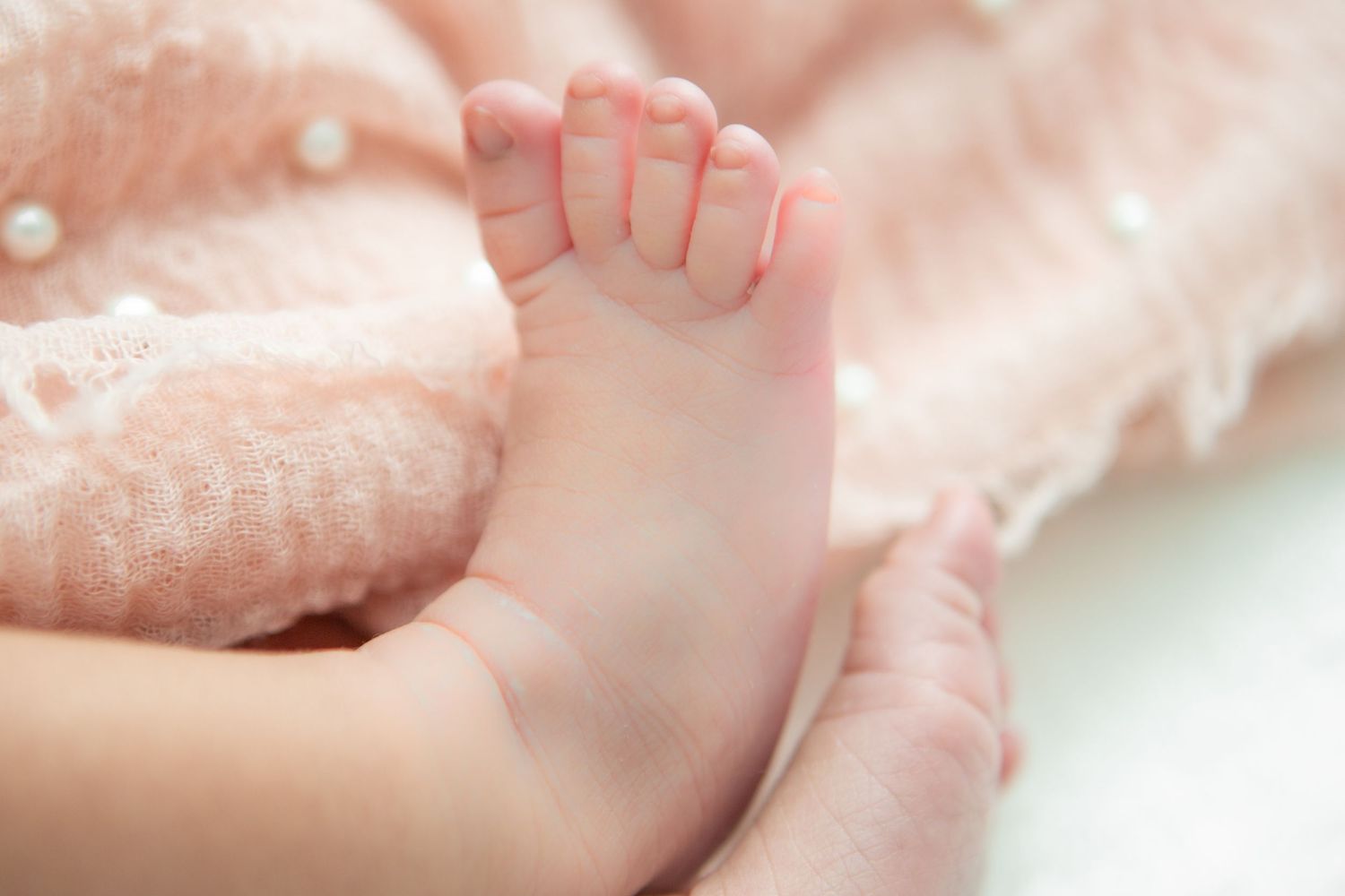Delicate close-up shots of baby's tiny features against pink fabric.