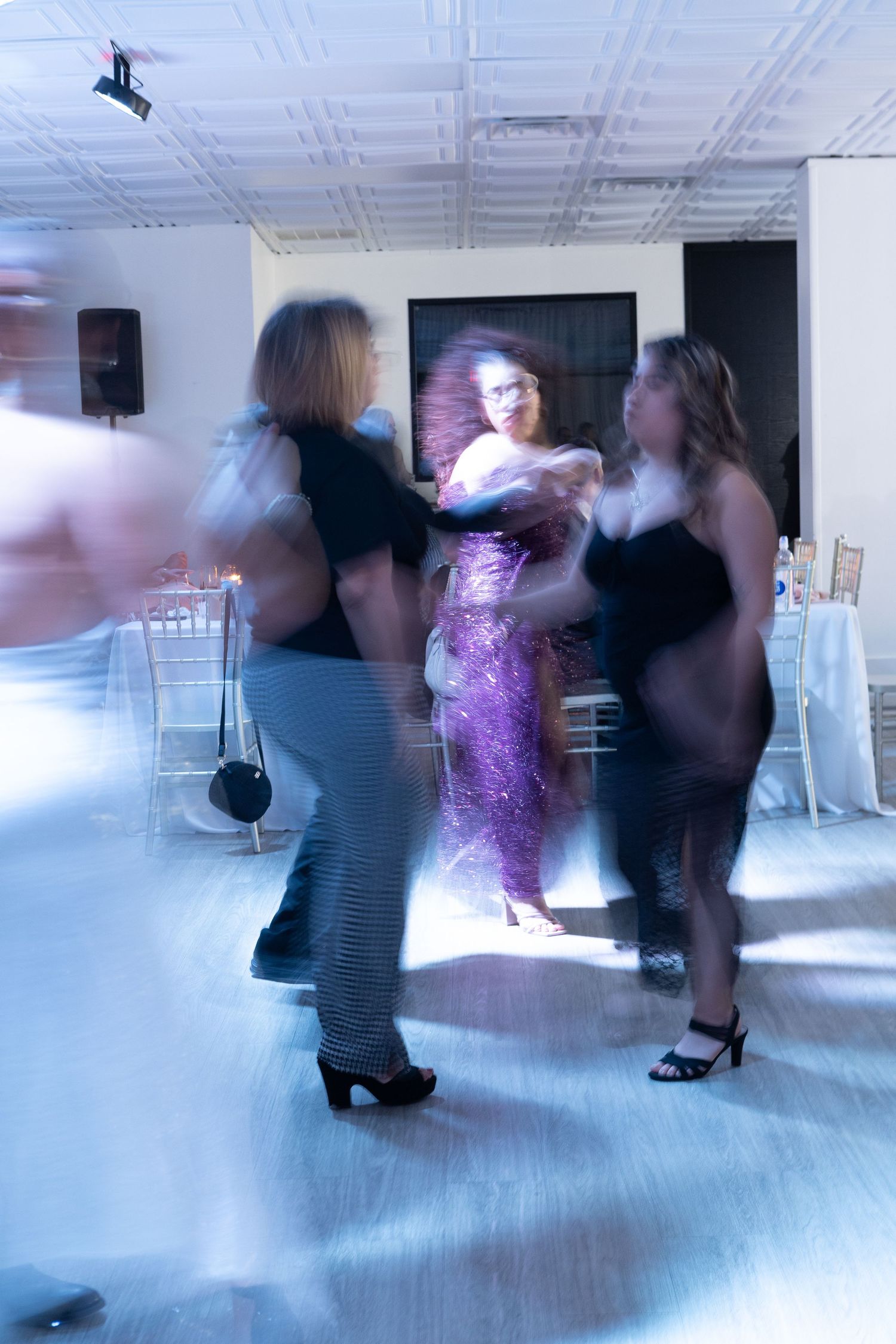 People dancing and celebrating at an indoor event with dramatic lighting effects.