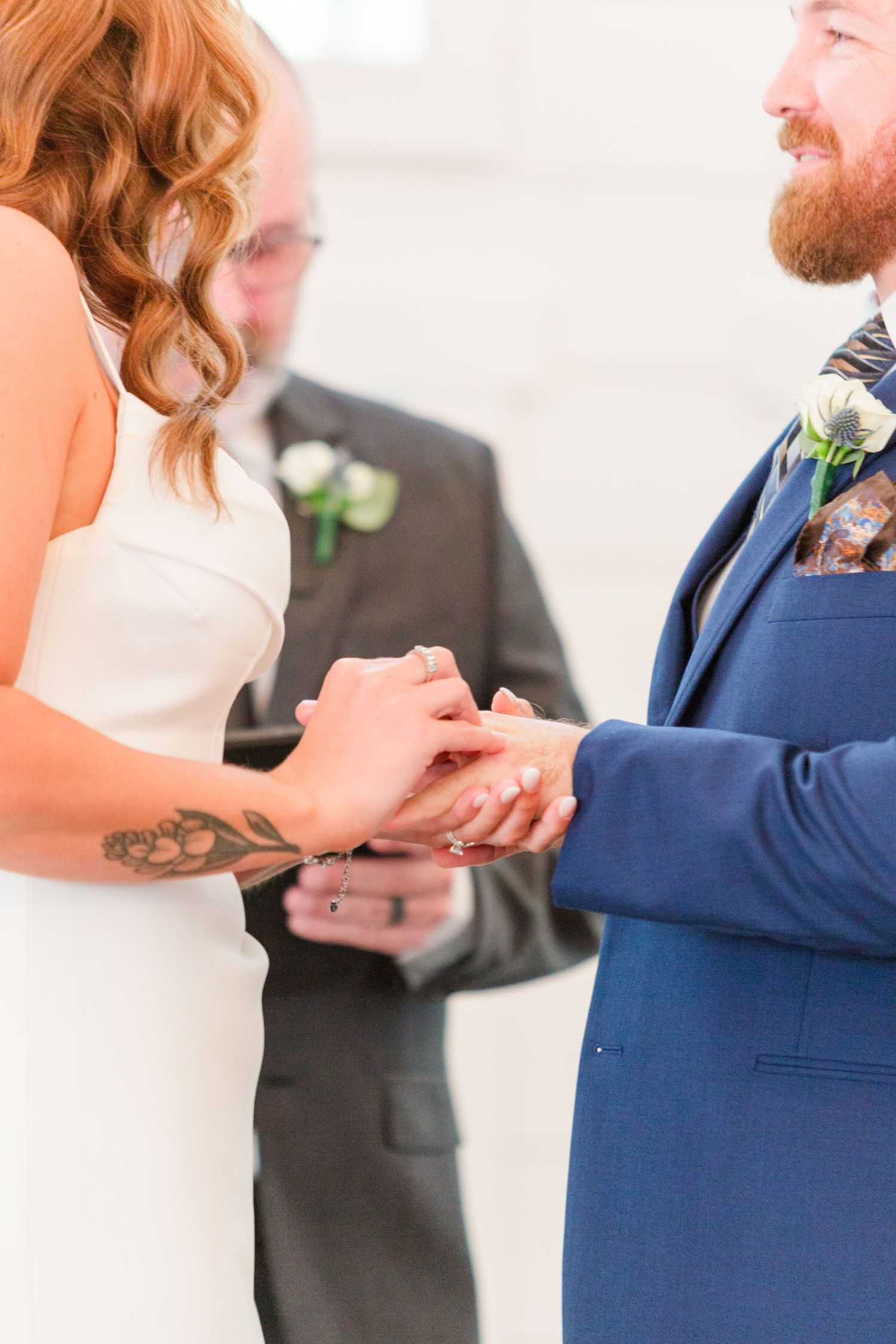 Bride and groom holding hands during ring exchange at ceremony.