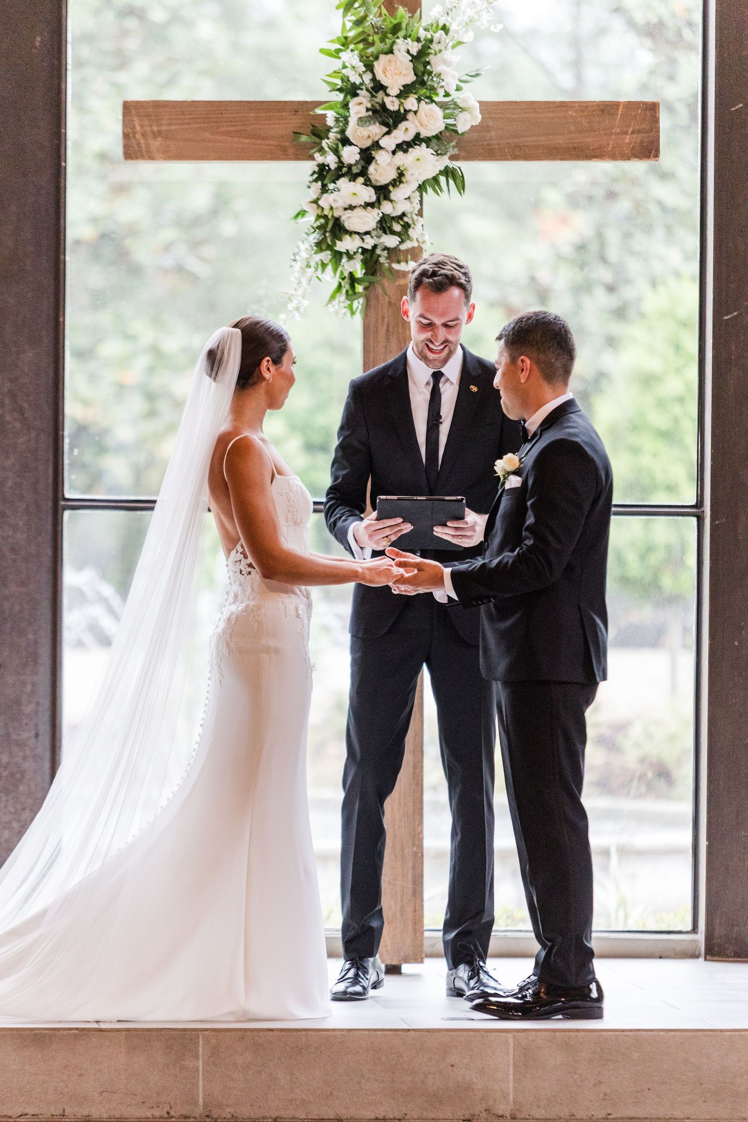 Intimate wedding ceremony in progress with natural light streaming through tall windows.