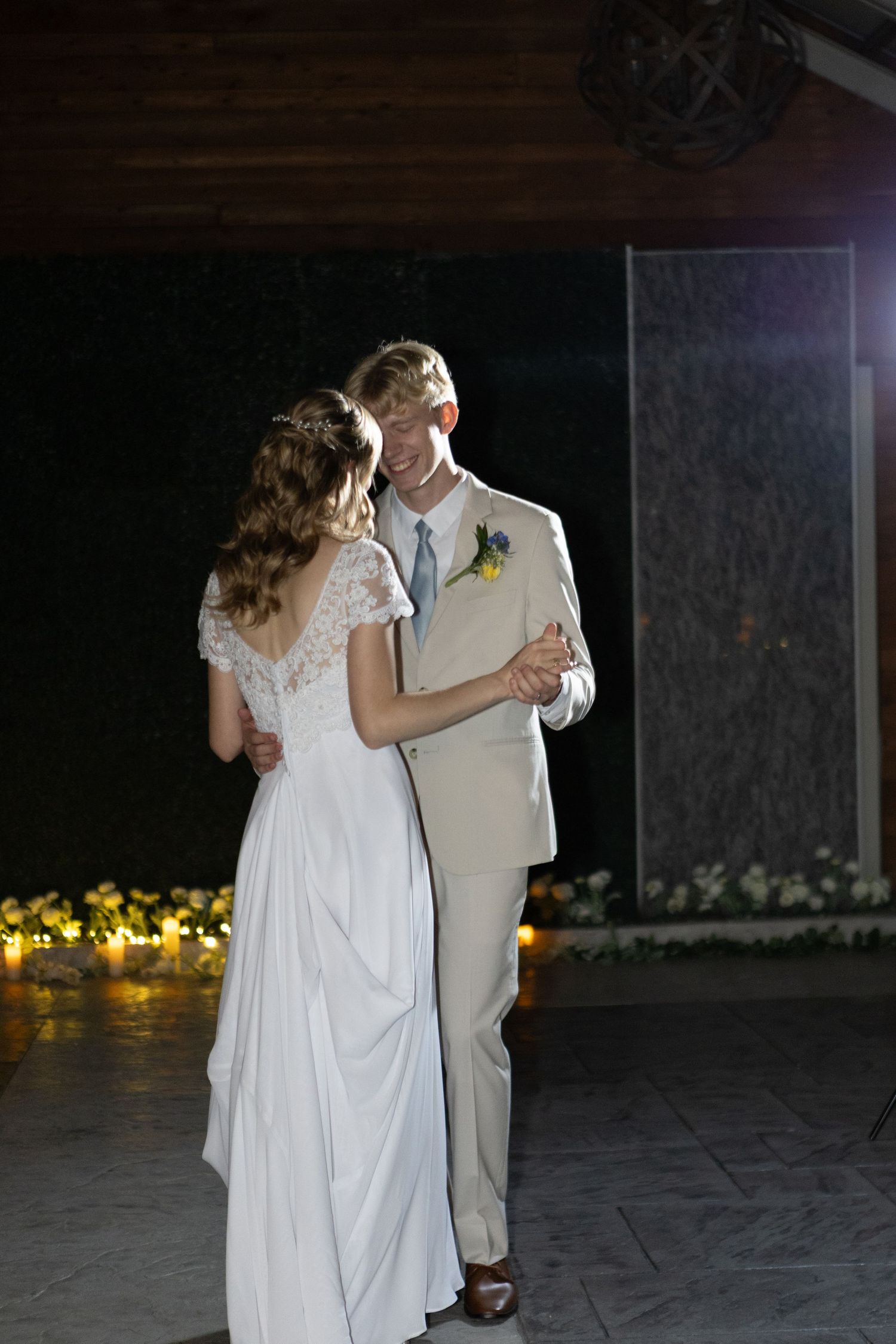 Bride and groom in white and cream attire dancing together during their wedding reception.
