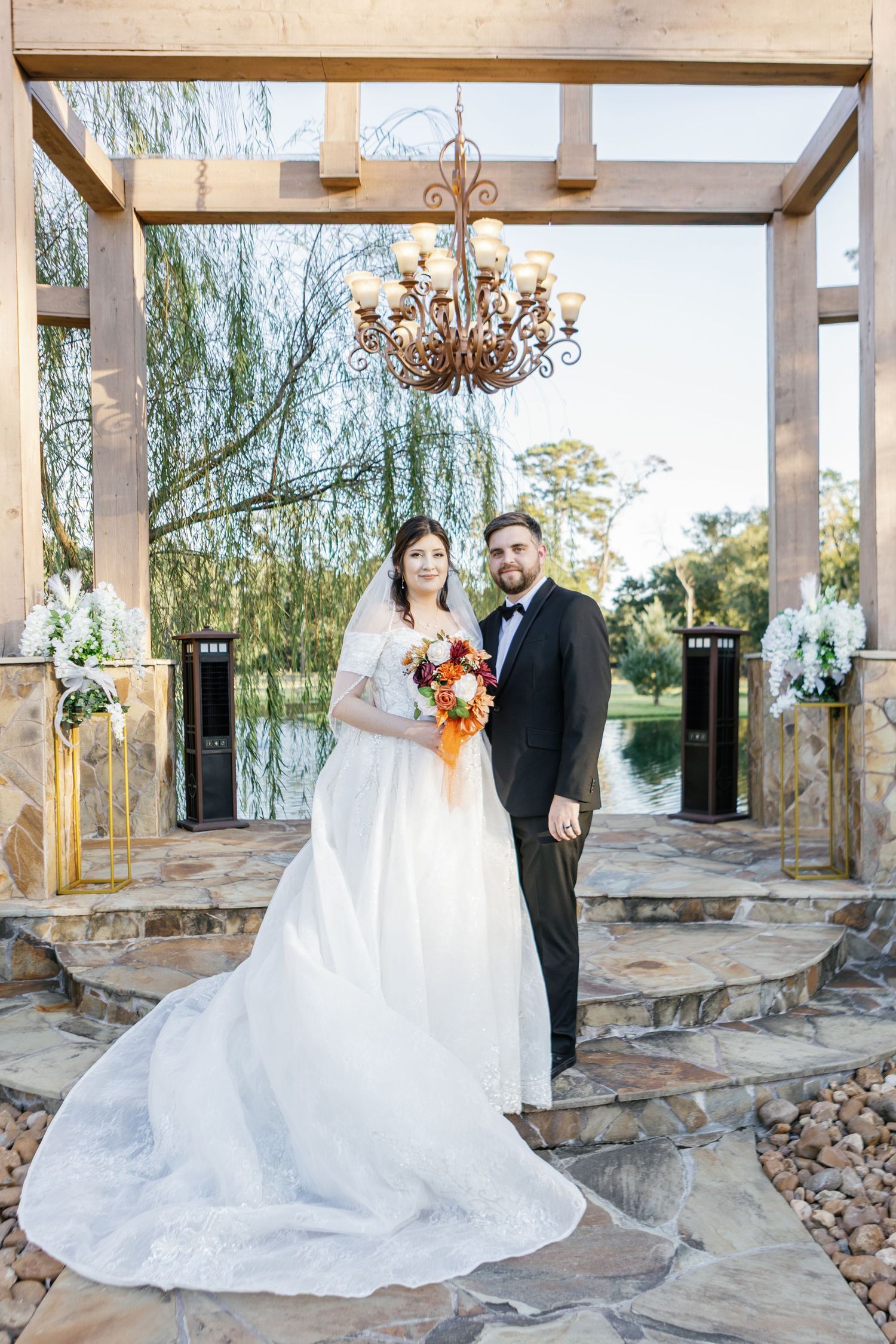 Bride and groom portrait session at a rustic stone venue with willow trees in background.