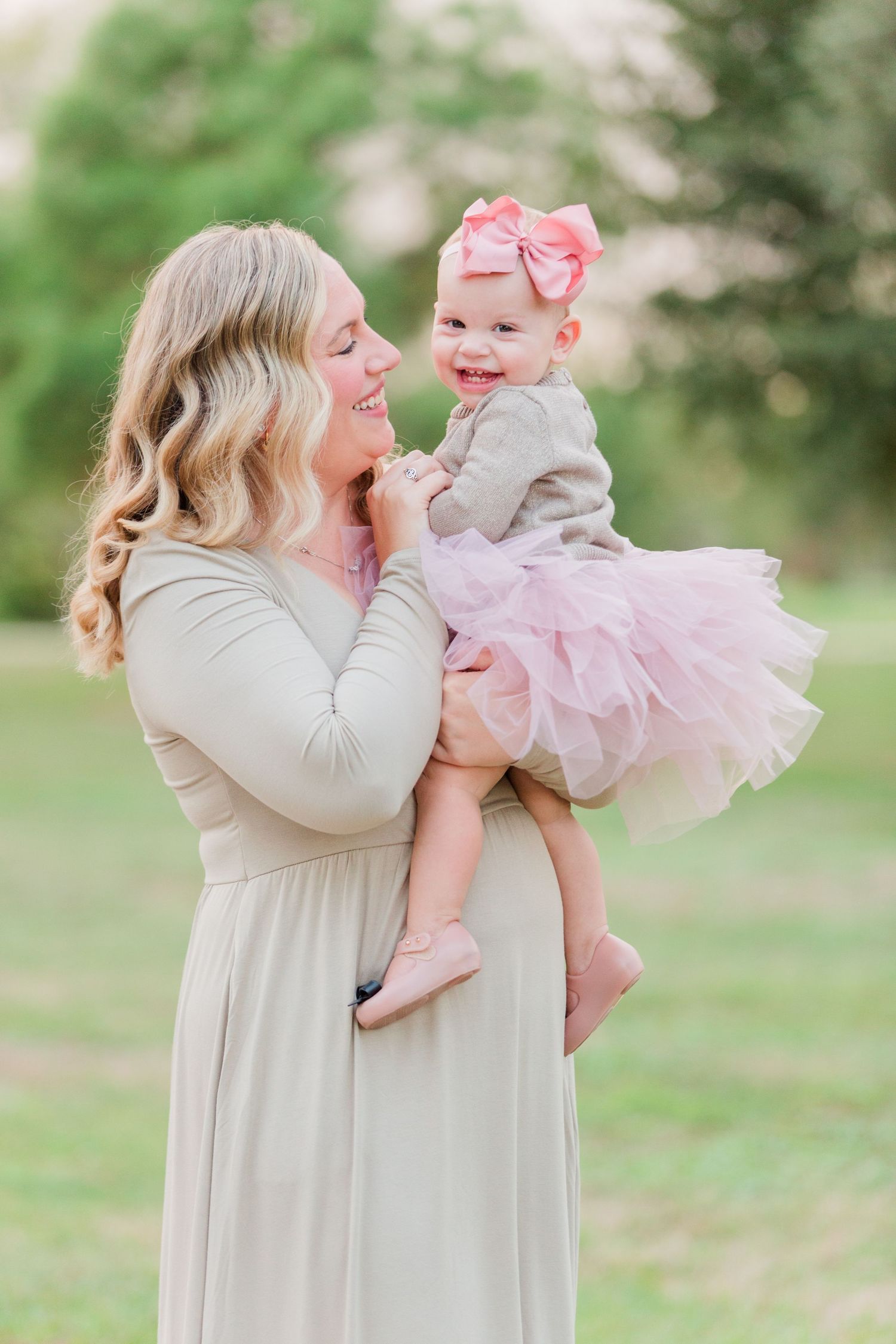 Mother and child in neutral and pink outfits playing together in spring garden setting.