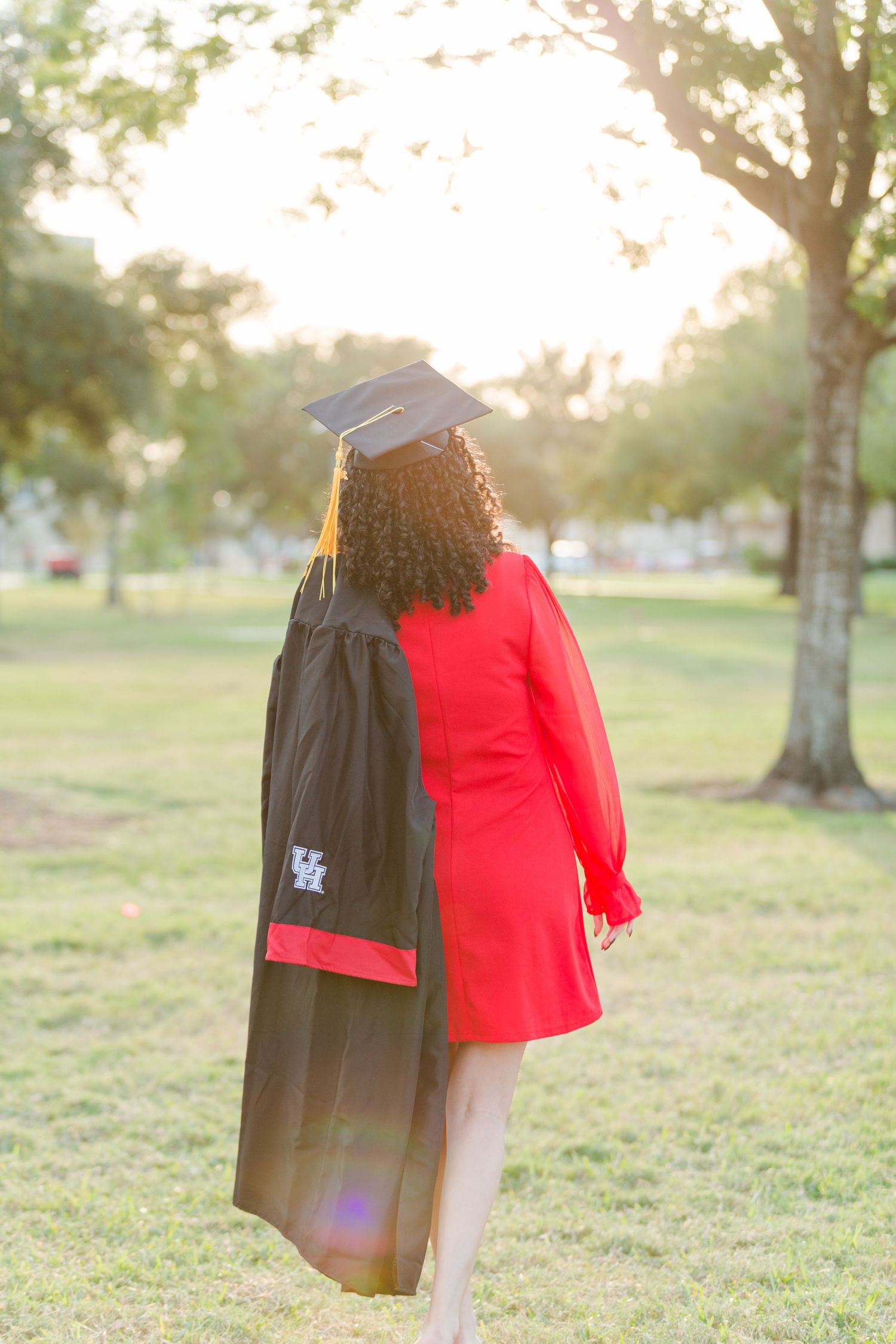Graduation photos in sunset with cap and gown against trees.