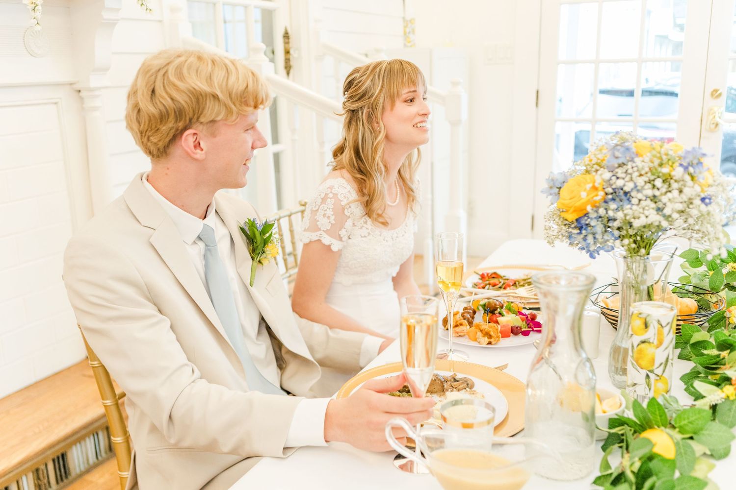 Elegant wedding reception with tables set with floral arrangements and natural lighting.