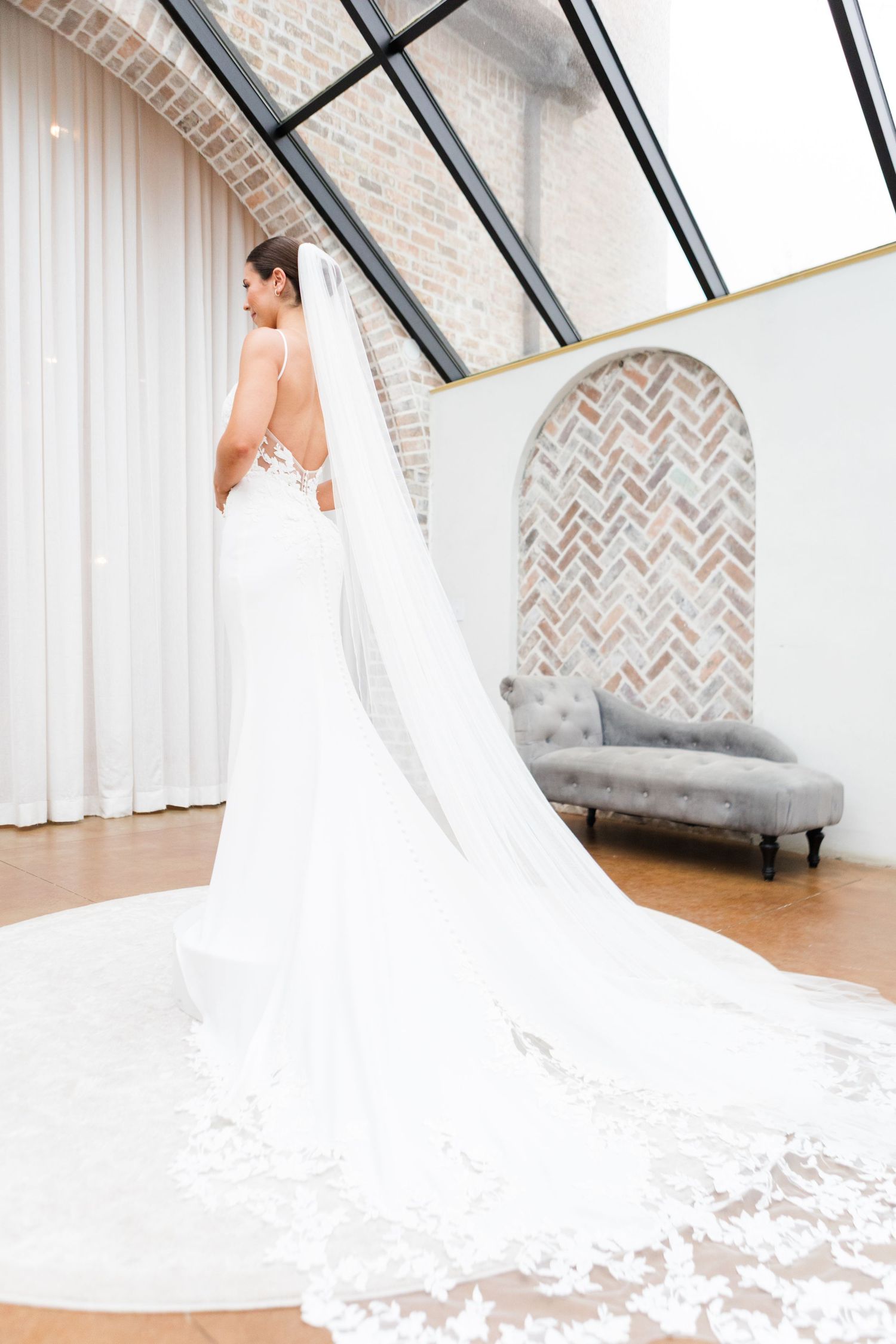 Long train of white wedding dress elegantly arranged in bright wedding venue.