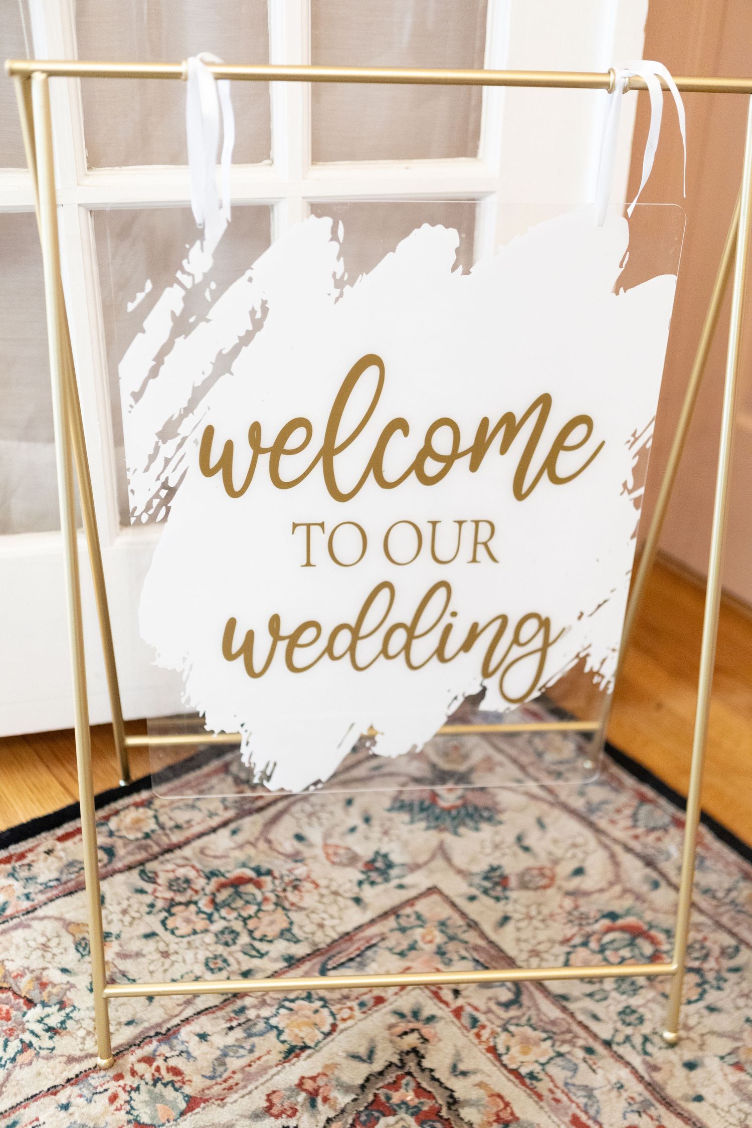 Gold welcome sign displayed on ornate vintage rug for wedding decor.