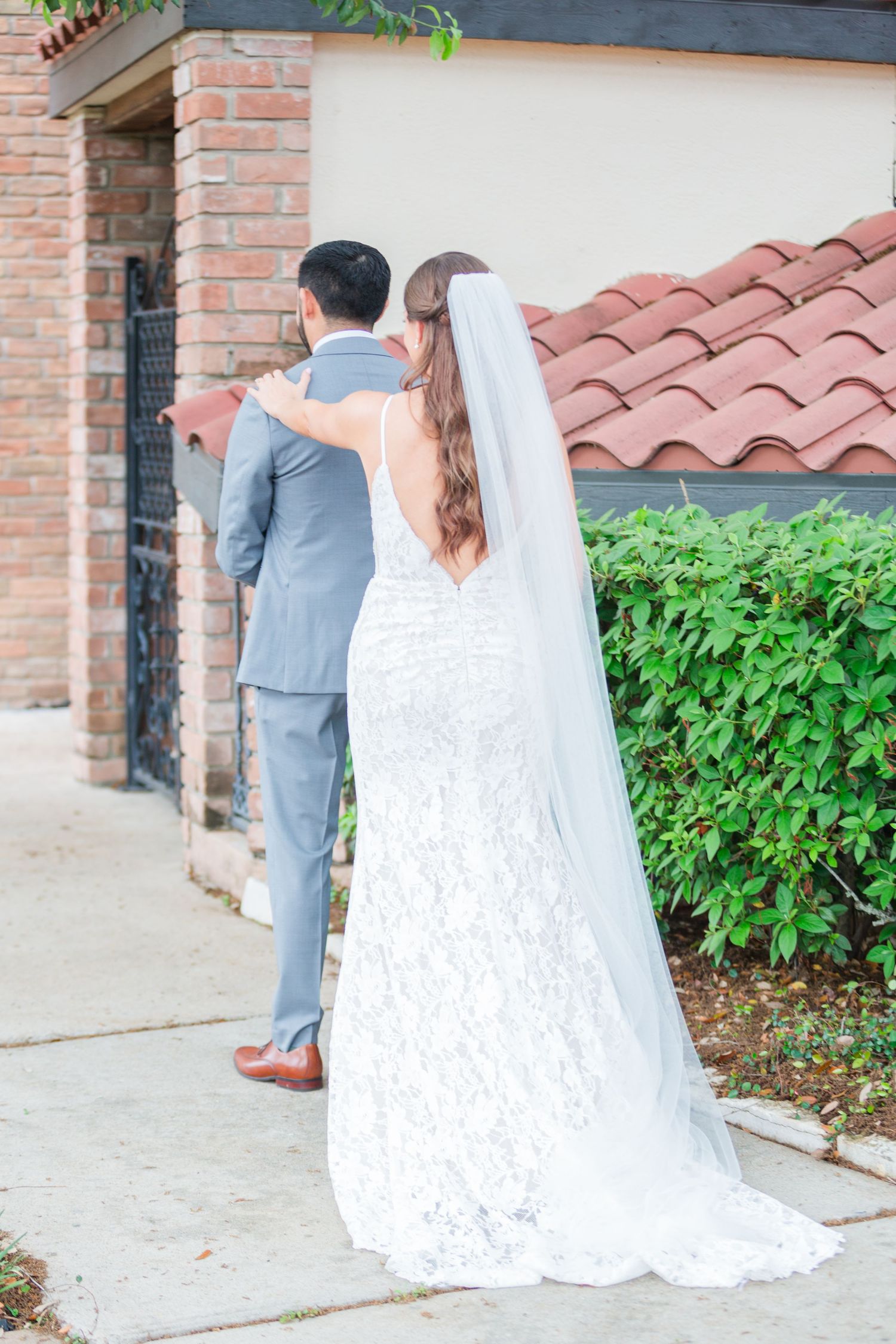 First look wedding moment captured outside a brick building with terracotta roof.