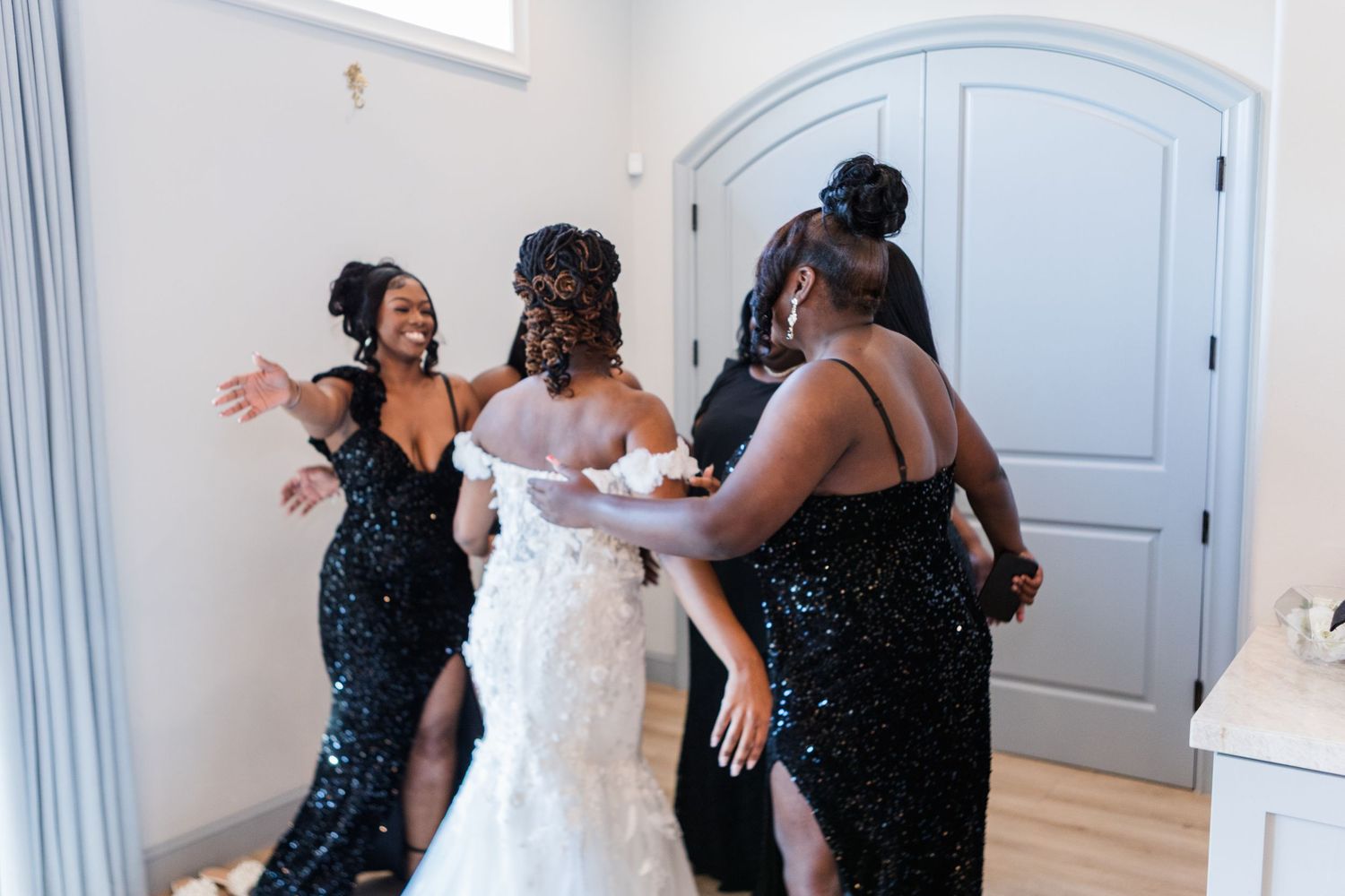 Bridesmaids in sparkling black dresses celebrate with the bride in a joyful moment.