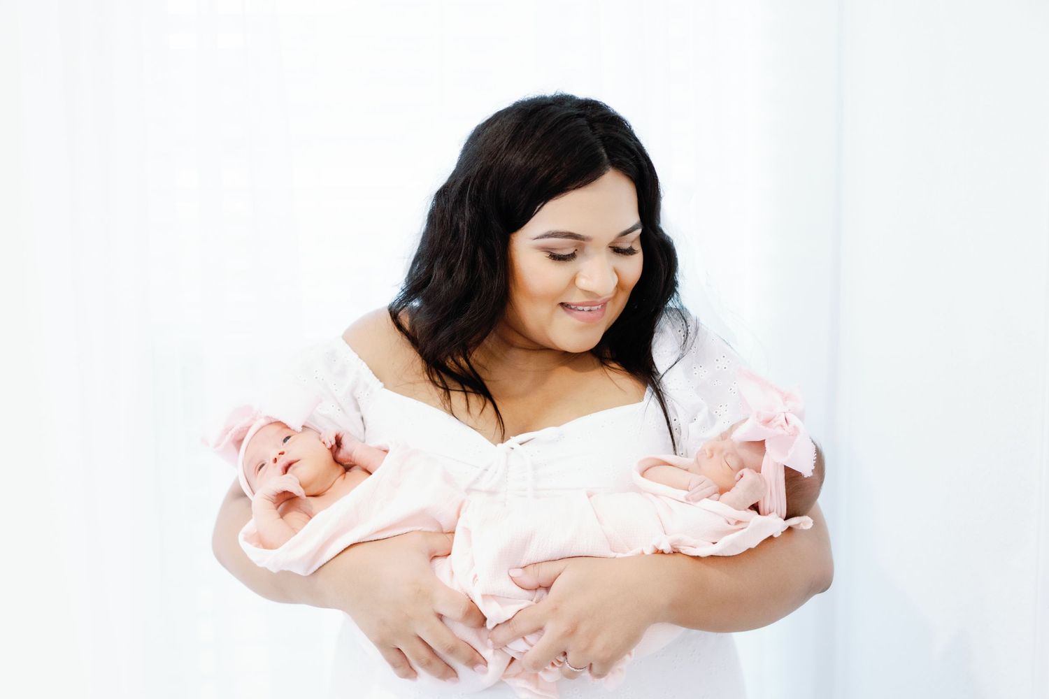 A newborn baby swaddled in pink cloth is gently held across a sequence of artistic portrait photos.