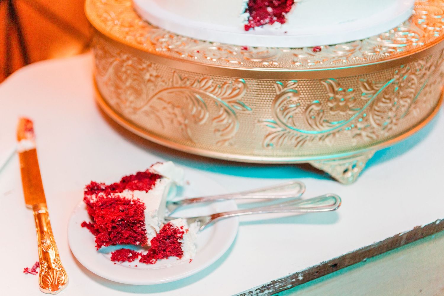 Close-up of elegant wedding cake plates with gold trim and red floral accents.
