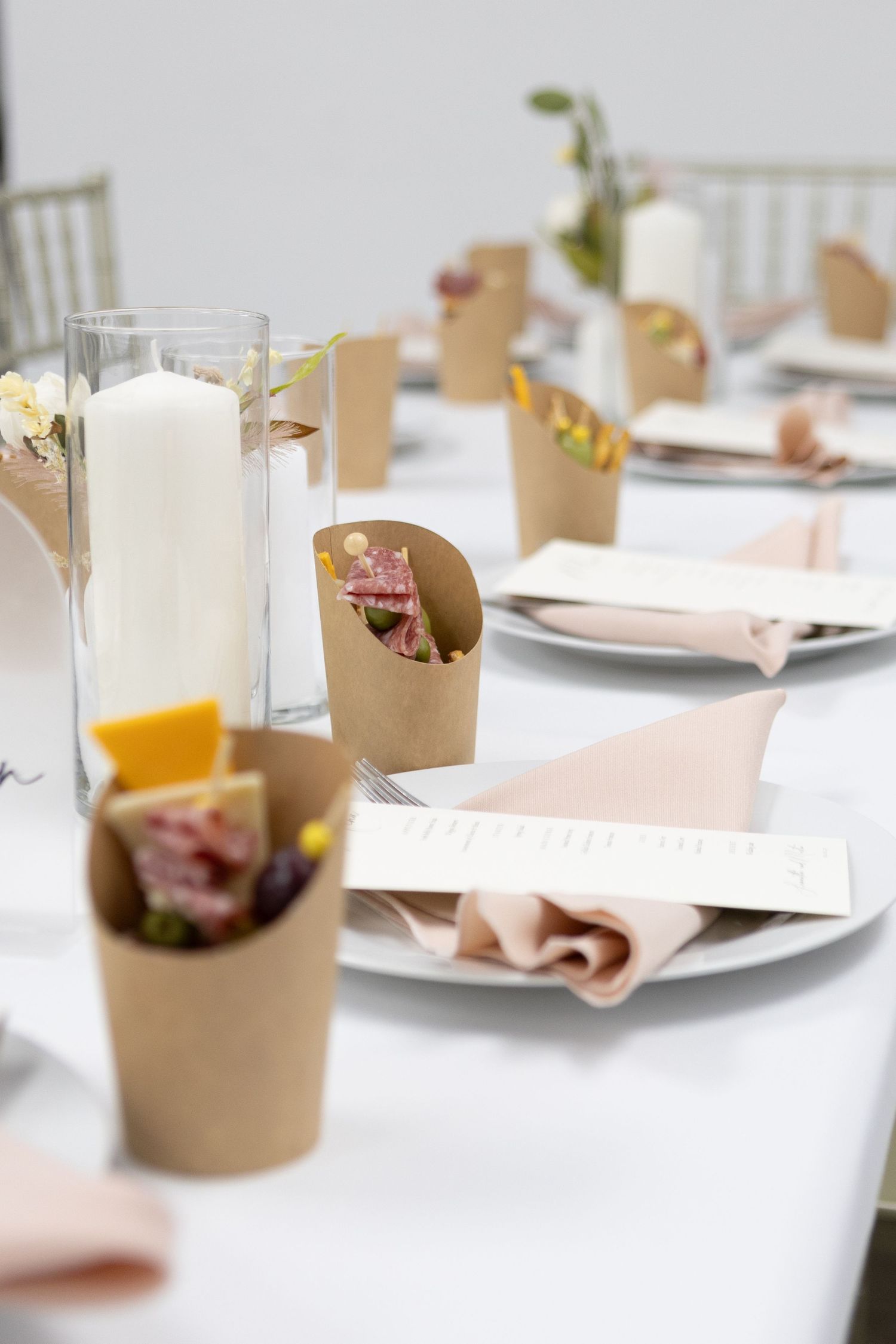 Modern wedding reception table decorated with white linens and kraft paper accents.