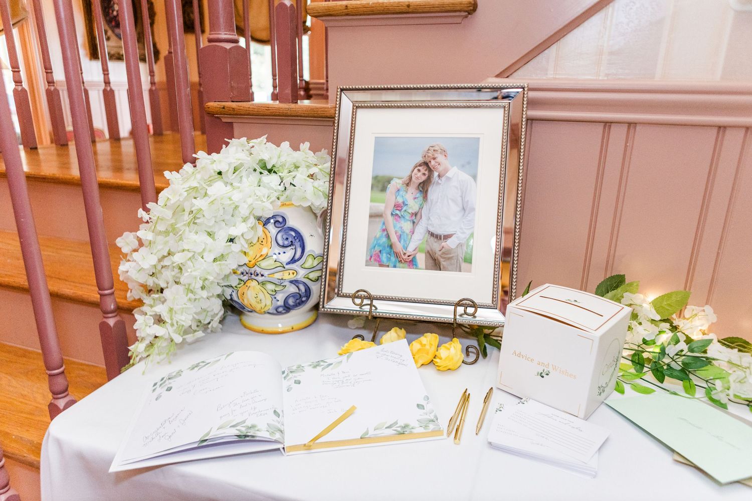 Wedding reception table setting with white floral centerpieces and framed photos in soft lighting.