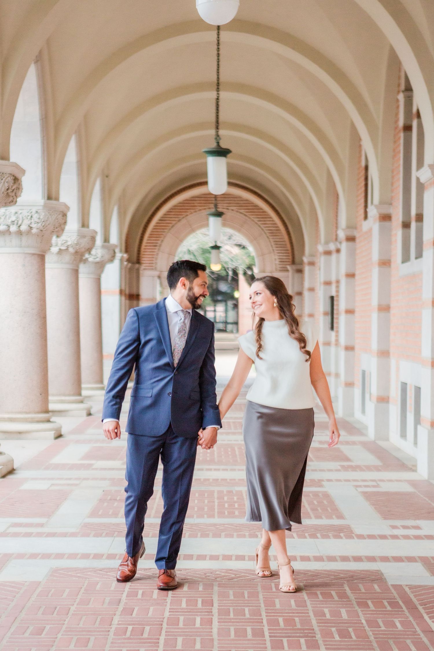Playful couple shares intimate moment under ornate archways.